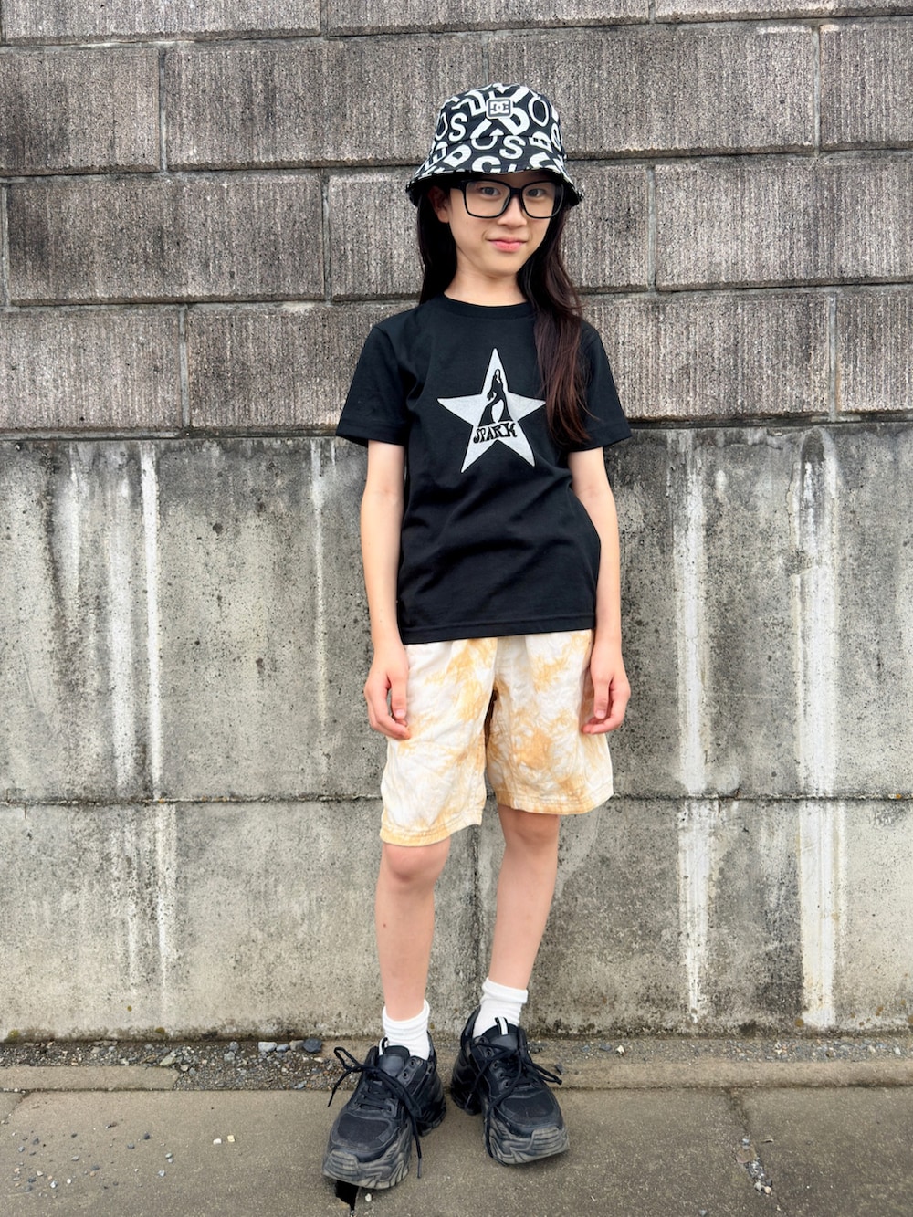 ブラウン系のその他パンツ、ブラック系のTシャツ/カットソー、ブラック系のハットを着用したキッズの夏コーディネートの2枚目の写真
