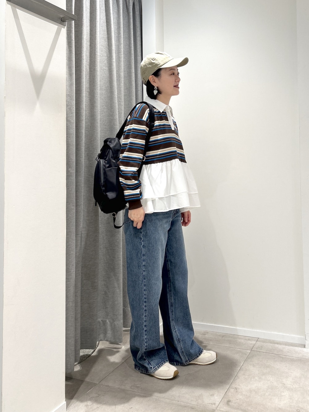 ブルー系のデニムパンツ、ブラック系のバックパック/リュック、ブラウン系のニット/セーターを着用したレディースの秋コーディネートの2枚目の写真