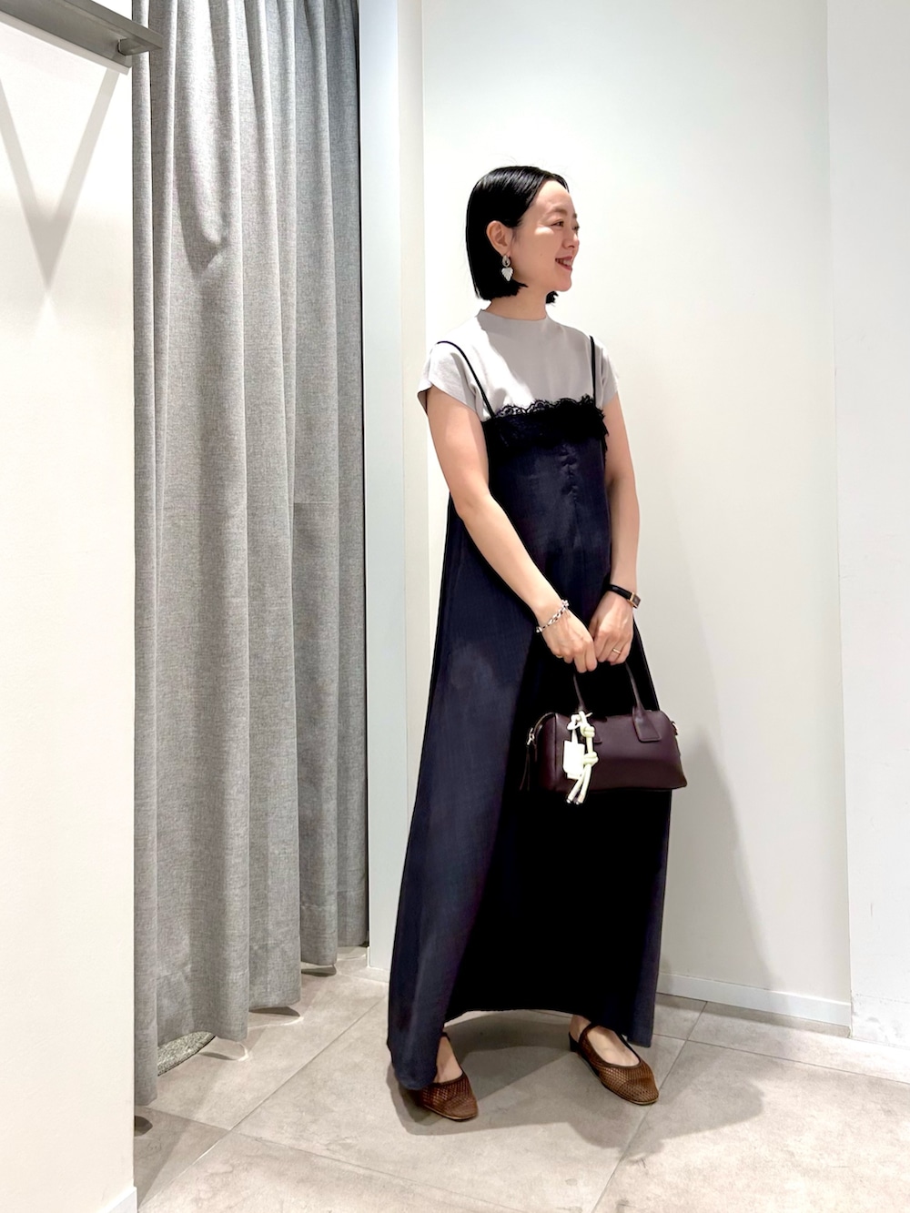グレー系のワンピース、ベージュ系のニット/セーター、ブラウン系のボストンバッグを着用したレディースの夏コーディネートの5枚目の写真