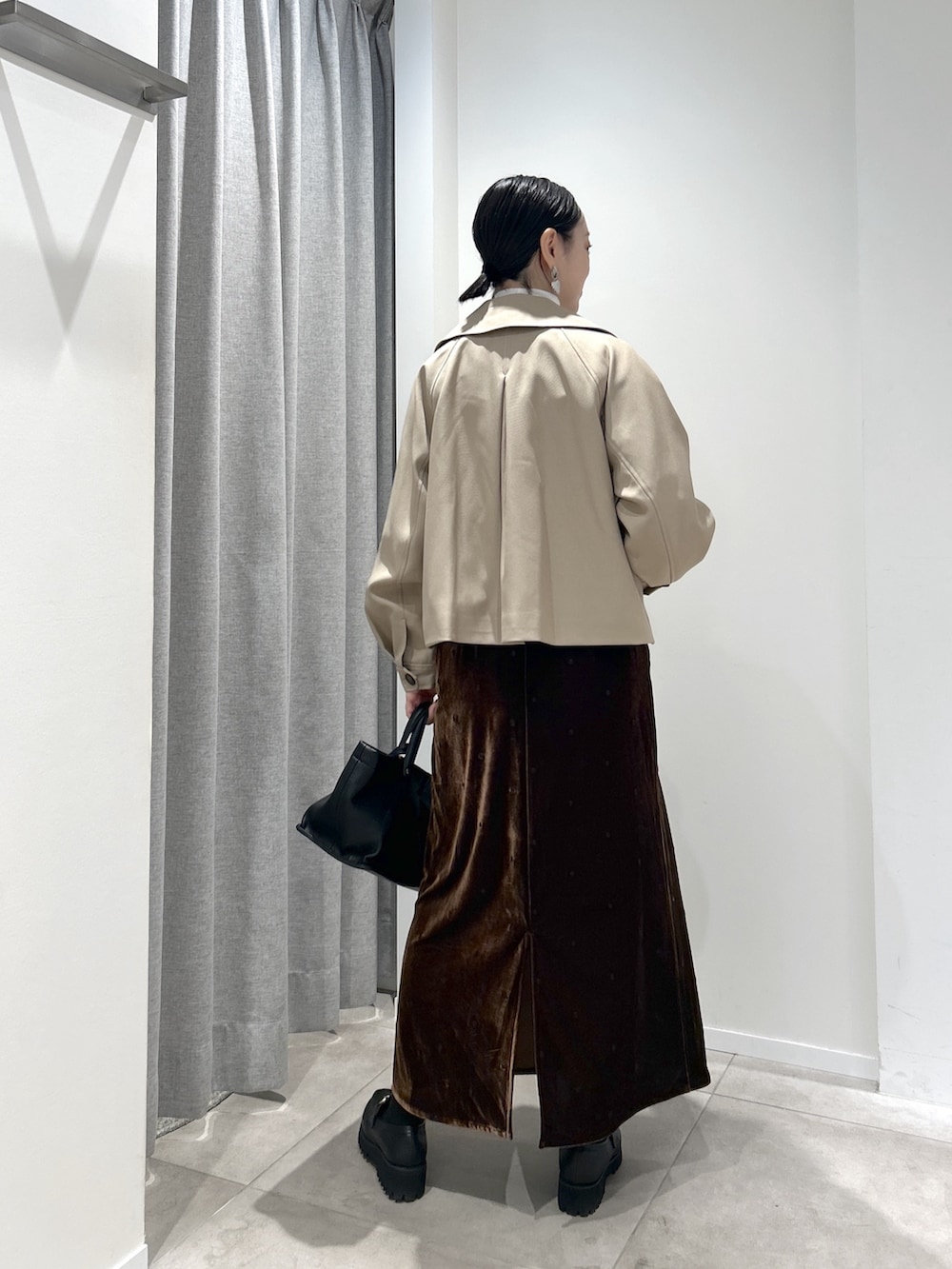ベージュ系のトレンチコート、ブラウン系のワンピース、ホワイト系のTシャツ/カットソーを着用したレディースの秋コーディネートの3枚目の写真