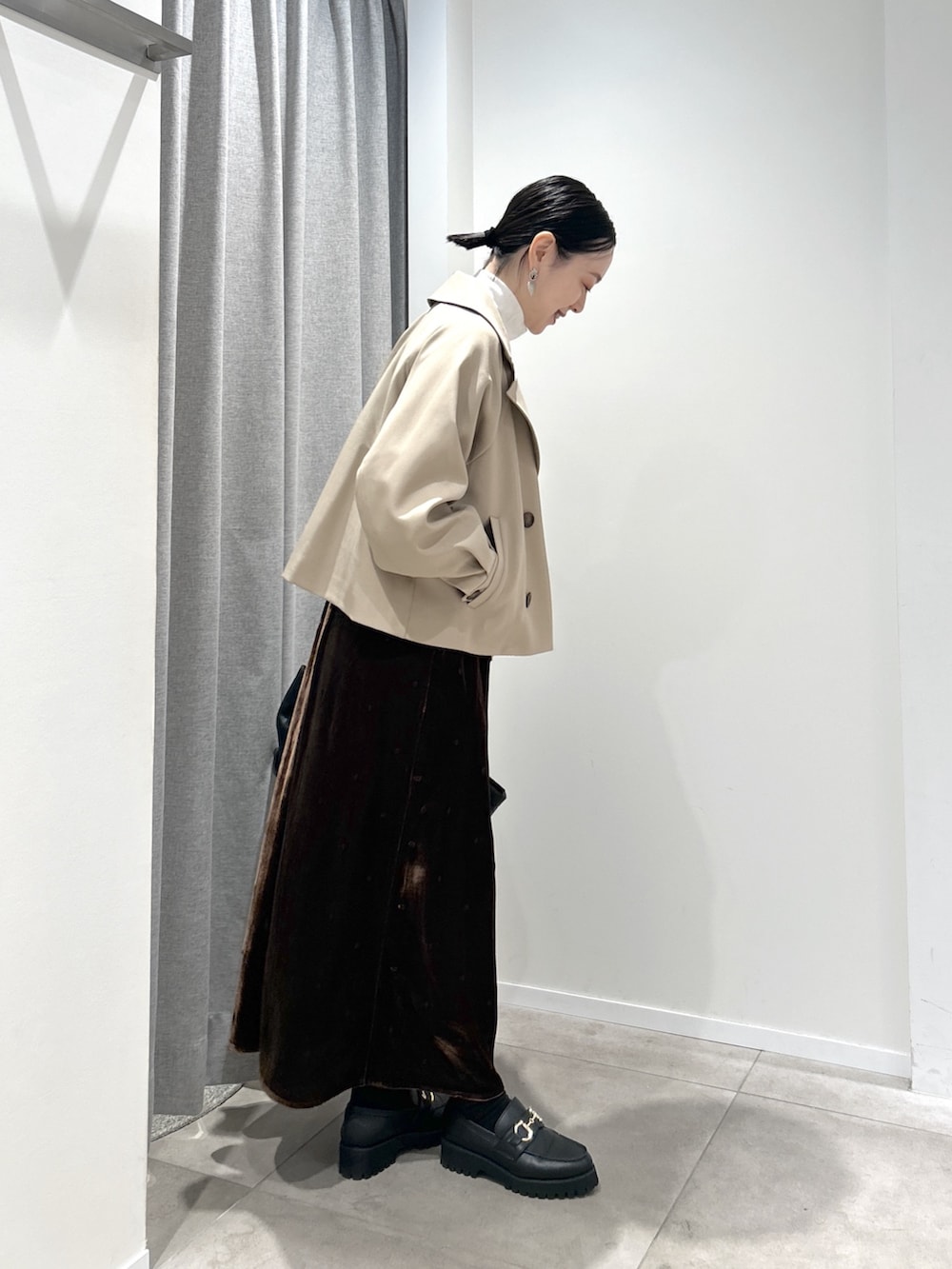 ベージュ系のトレンチコート、ブラウン系のワンピース、ホワイト系のTシャツ/カットソーを着用したレディースの秋コーディネートの2枚目の写真