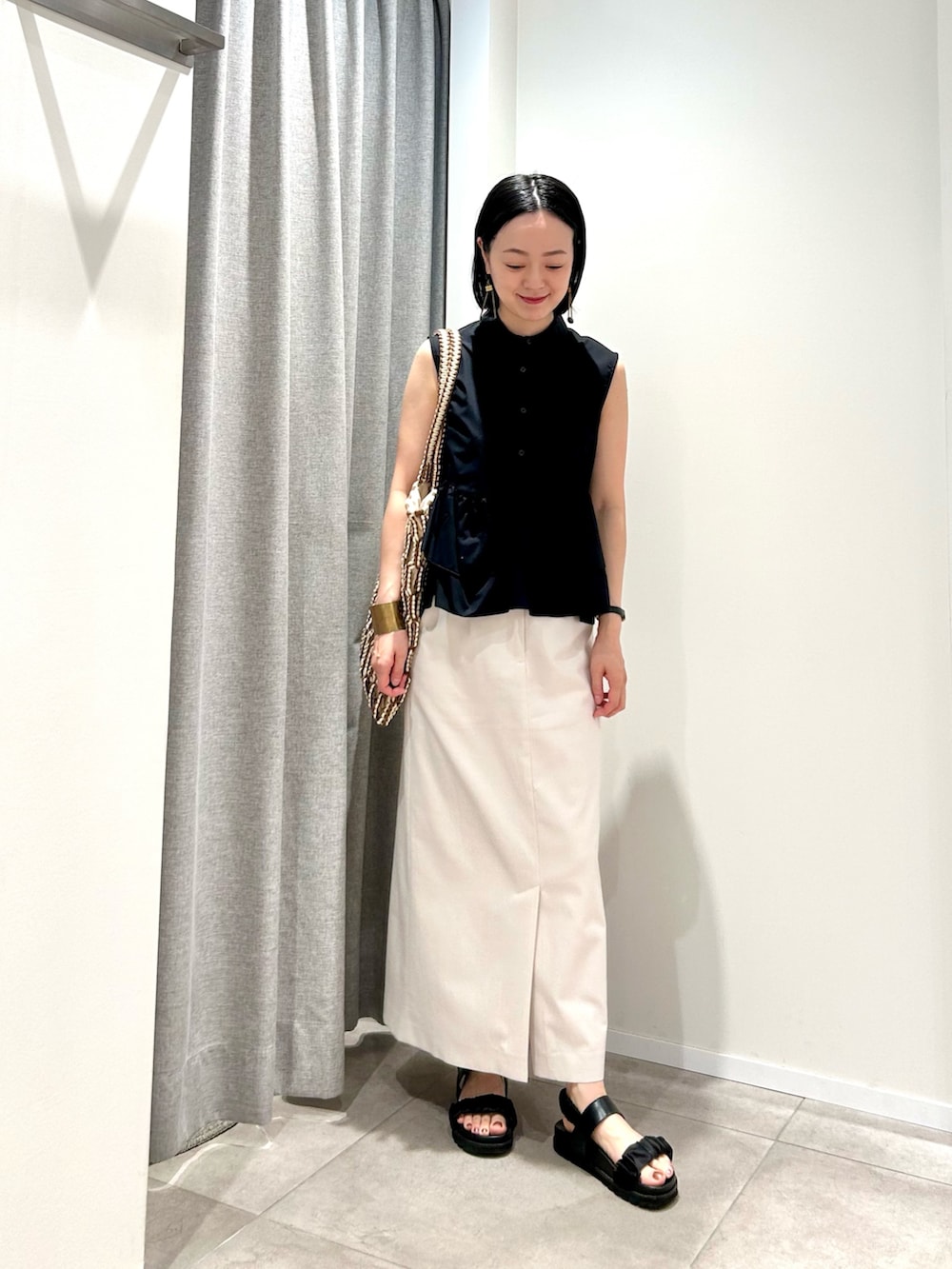 ブラック系のシャツ/ブラウス、ホワイト系のスカート、ブラウン系のトートバッグを着用したレディースの夏コーディネートの2枚目の写真