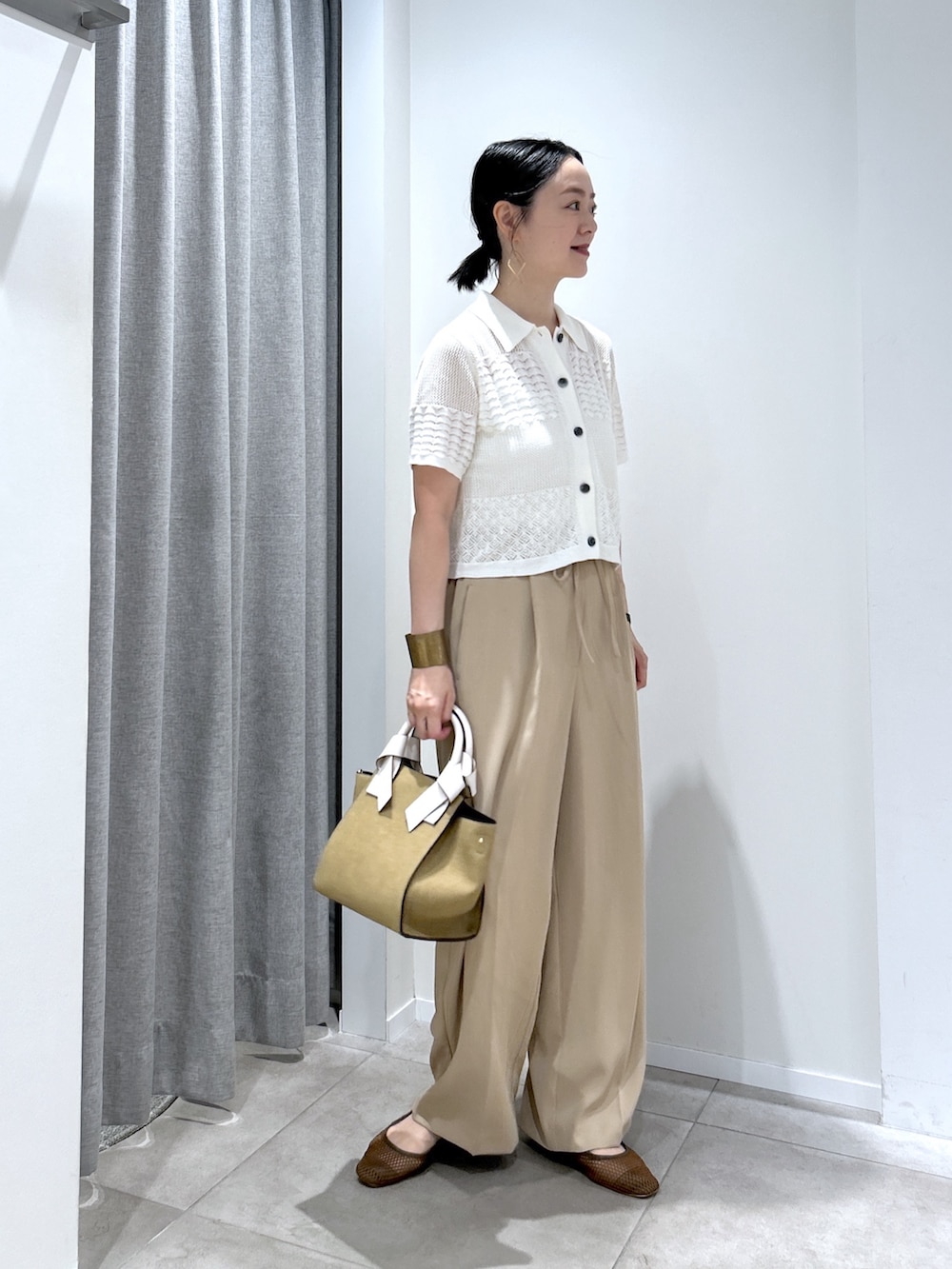 イエロー系のその他パンツ、ホワイト系のカーディガン/ボレロ、ベージュ系のトートバッグを着用したレディースの夏コーディネートの2枚目の写真