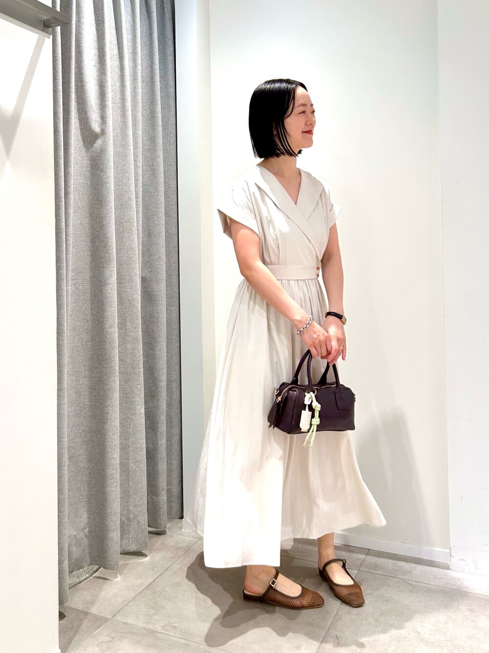 ホワイト系のワンピース、ブラウン系のボストンバッグ、ブラウン系のサンダルを着用したレディースの夏コーディネートの6枚目の写真