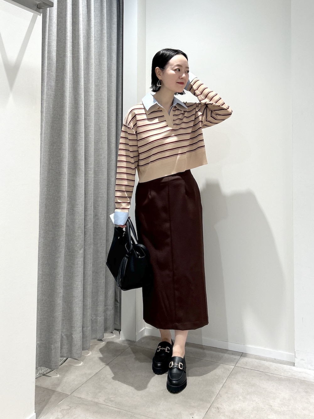 ベージュ系のニット/セーター、ブラウン系のスカート、ブラック系のトートバッグを着用したレディースの夏コーディネートの2枚目の写真