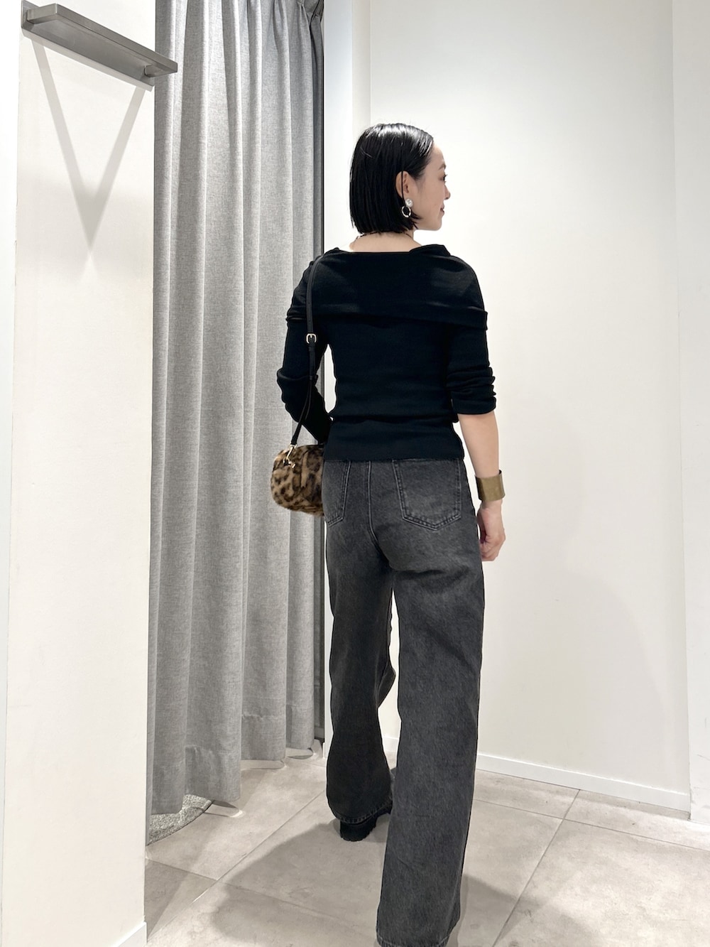ブラック系のニット/セーター、ブラック系のデニムパンツ、ブラウン系のボストンバッグを着用したレディースの秋コーディネートの3枚目の写真
