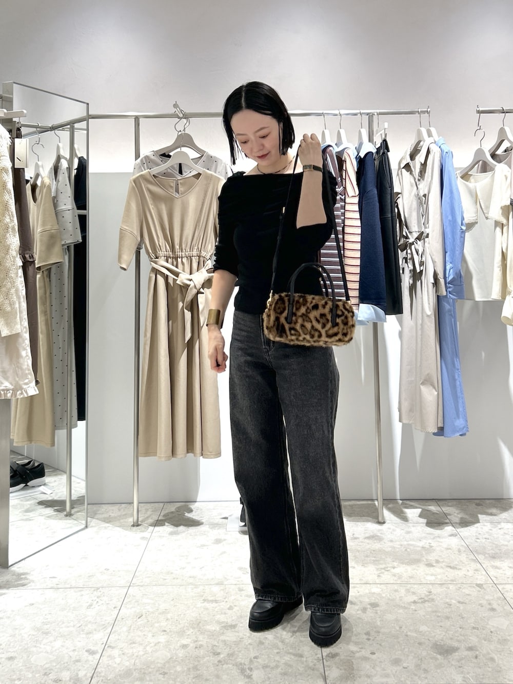 ブラック系のニット/セーター、ブラック系のデニムパンツ、ブラウン系のボストンバッグを着用したレディースの秋コーディネートの4枚目の写真