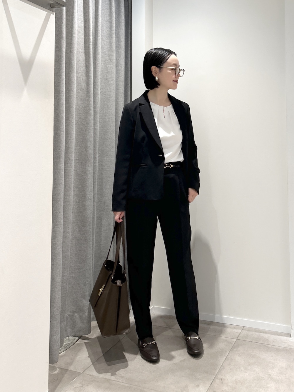 ブラック系のテーラードジャケット、ブラック系のその他パンツ、ブラウン系のトートバッグを着用したレディースの秋コーディネートの5枚目の写真