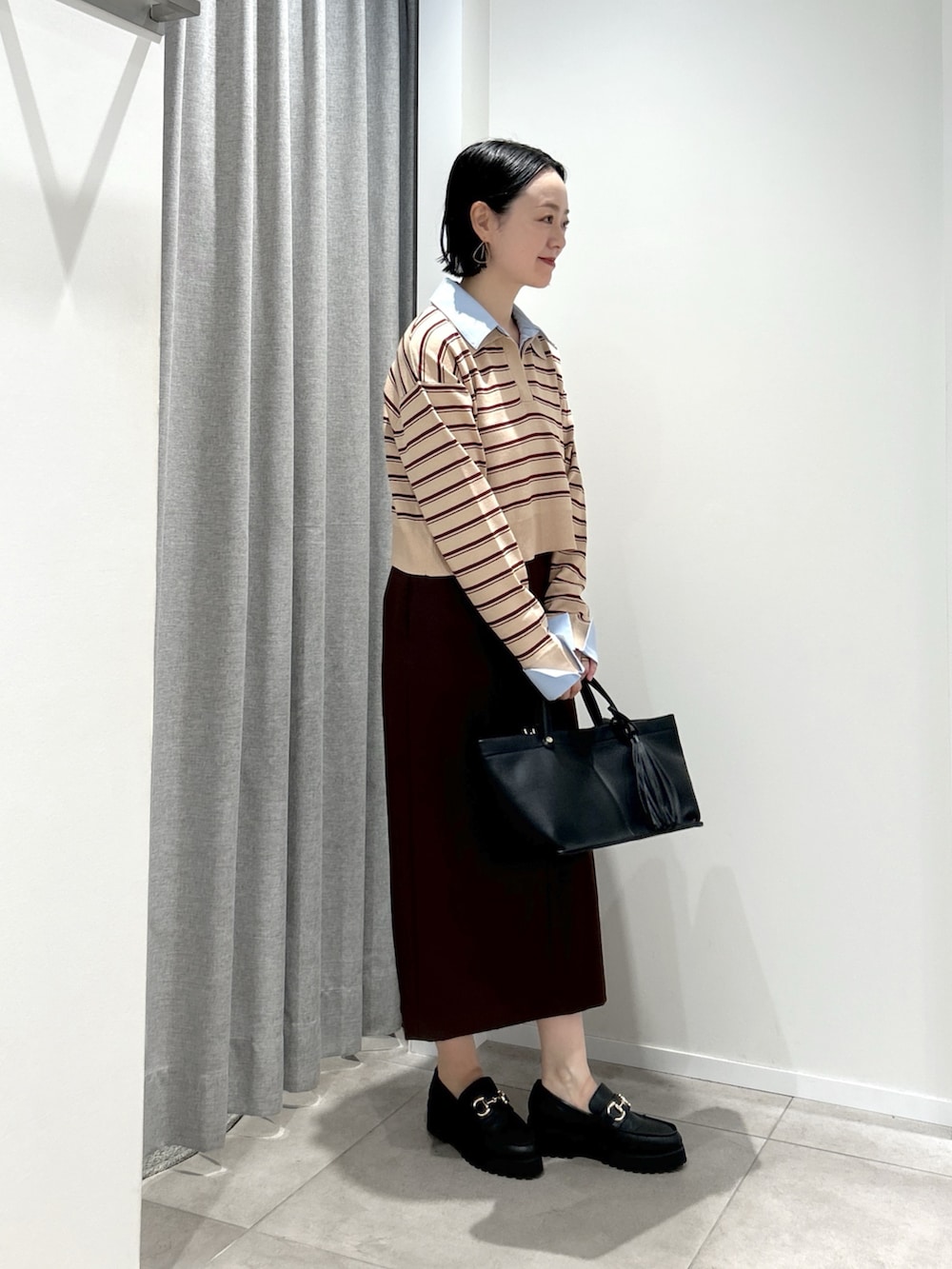 ベージュ系のニット/セーター、ブラウン系のスカート、ブラック系のトートバッグを着用したレディースの夏コーディネートの3枚目の写真