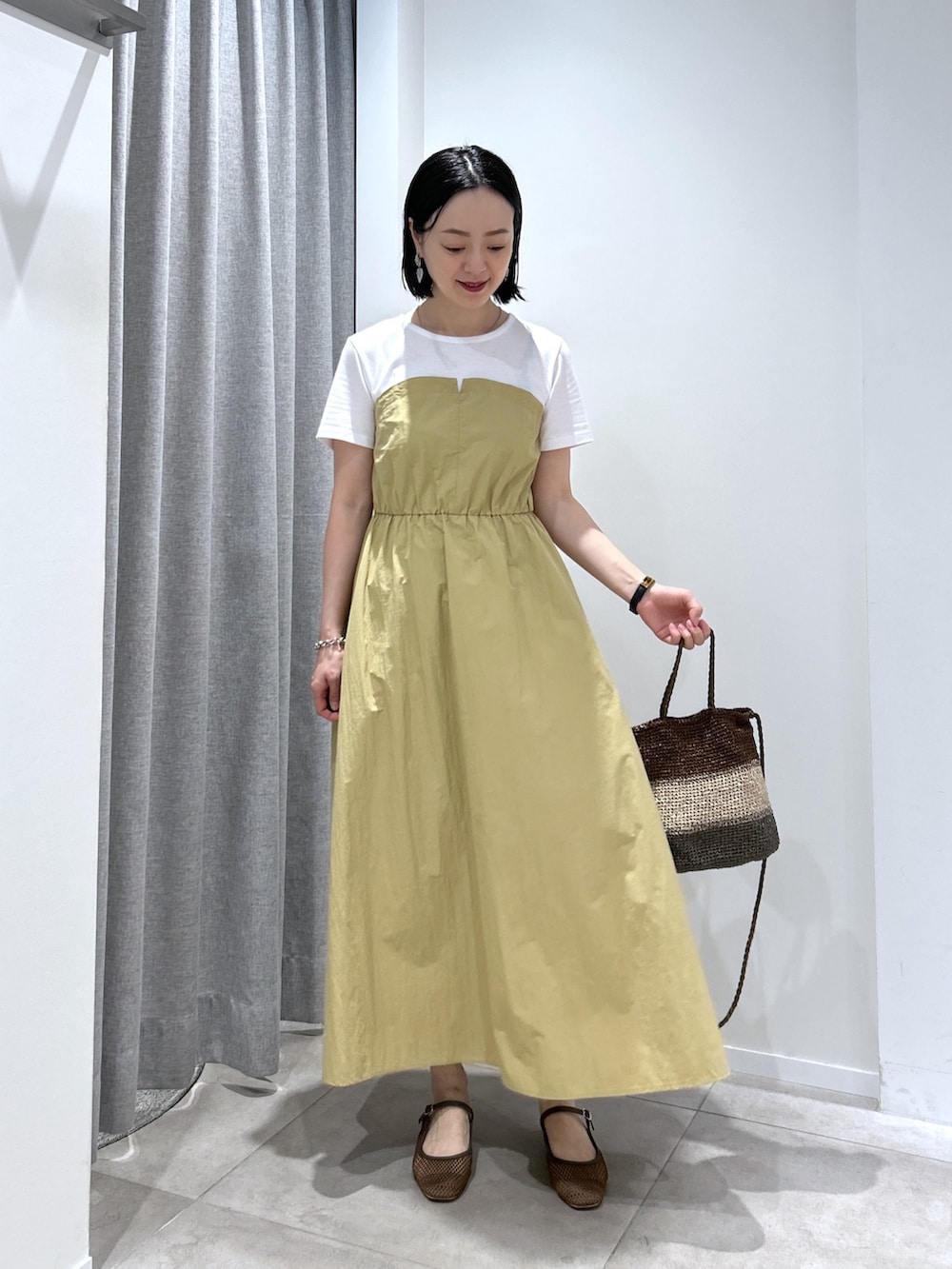 ベージュ系のワンピース、ゴールド系のハンドバッグ、ブラウン系のサンダルを着用したレディースの夏コーディネートの2枚目の写真