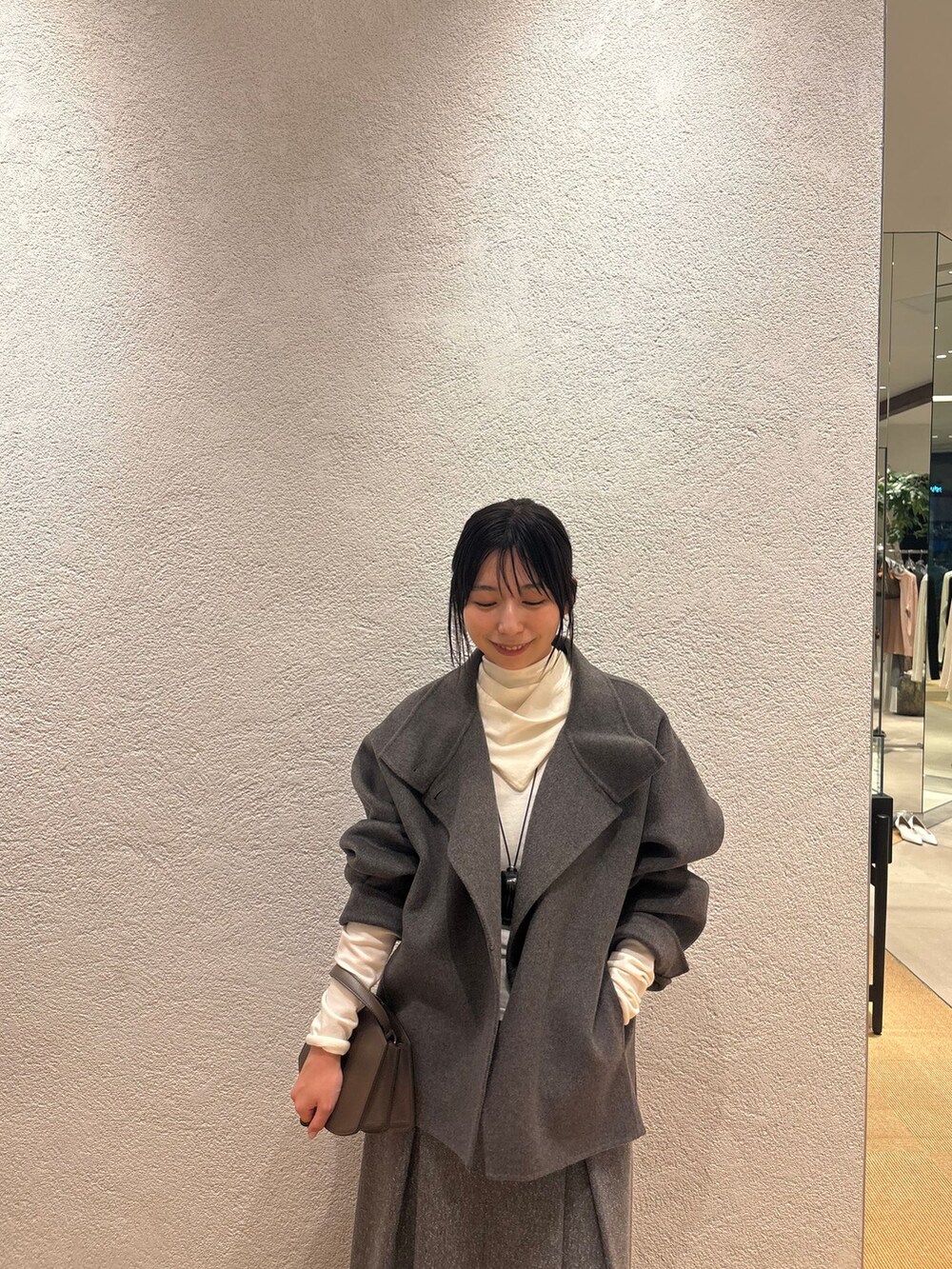 グレー系のその他アウター、グレー系のスカート、ホワイト系のニット/セーターを着用したレディースの秋コーディネートの4枚目の写真