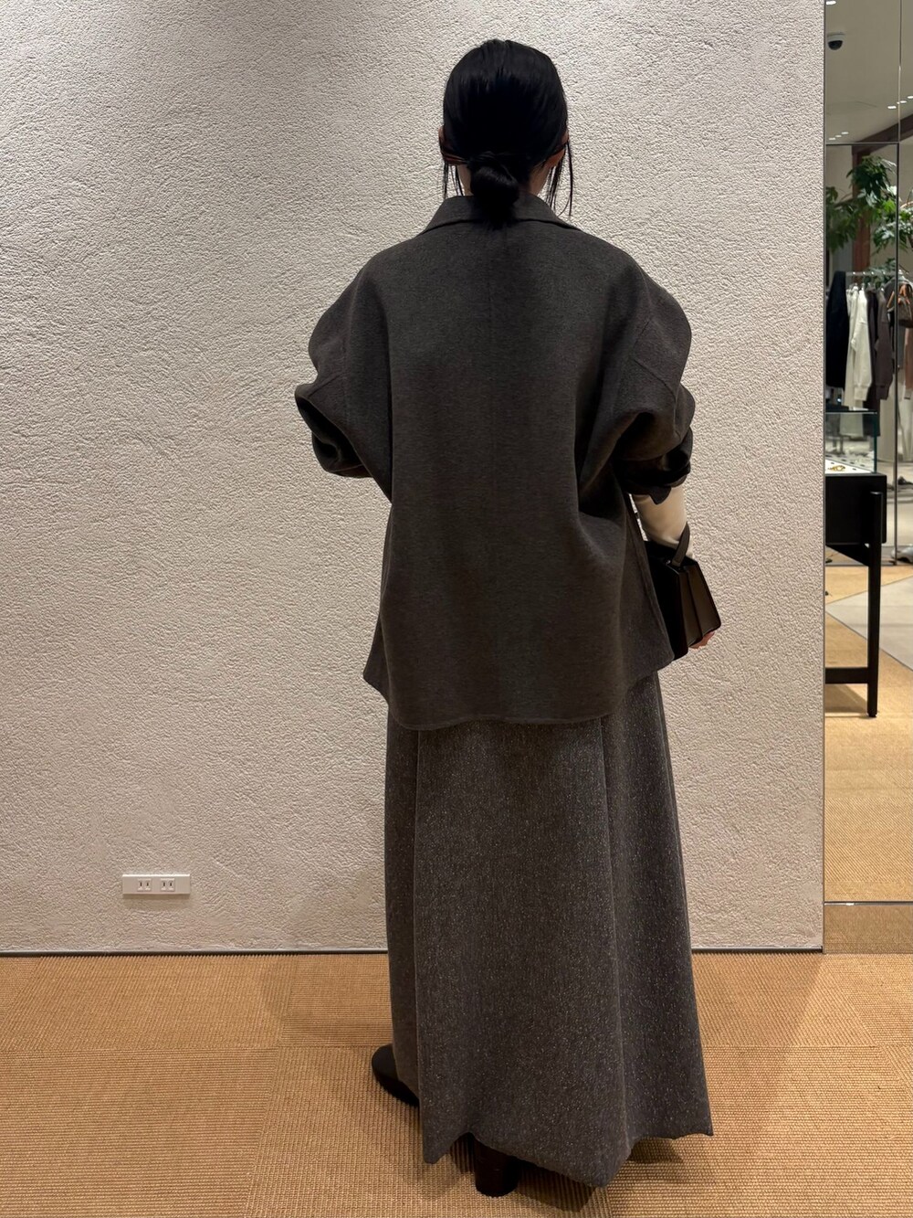 グレー系のその他アウター、グレー系のスカート、ホワイト系のニット/セーターを着用したレディースの秋コーディネートの3枚目の写真