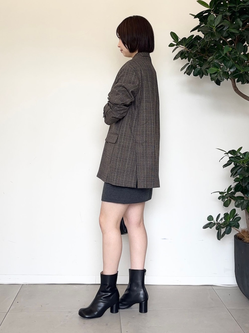 グレー系のスカート、グレー系のTシャツ/カットソー、ブラック系のクラッチバッグを着用したレディースの秋コーディネートの2枚目の写真