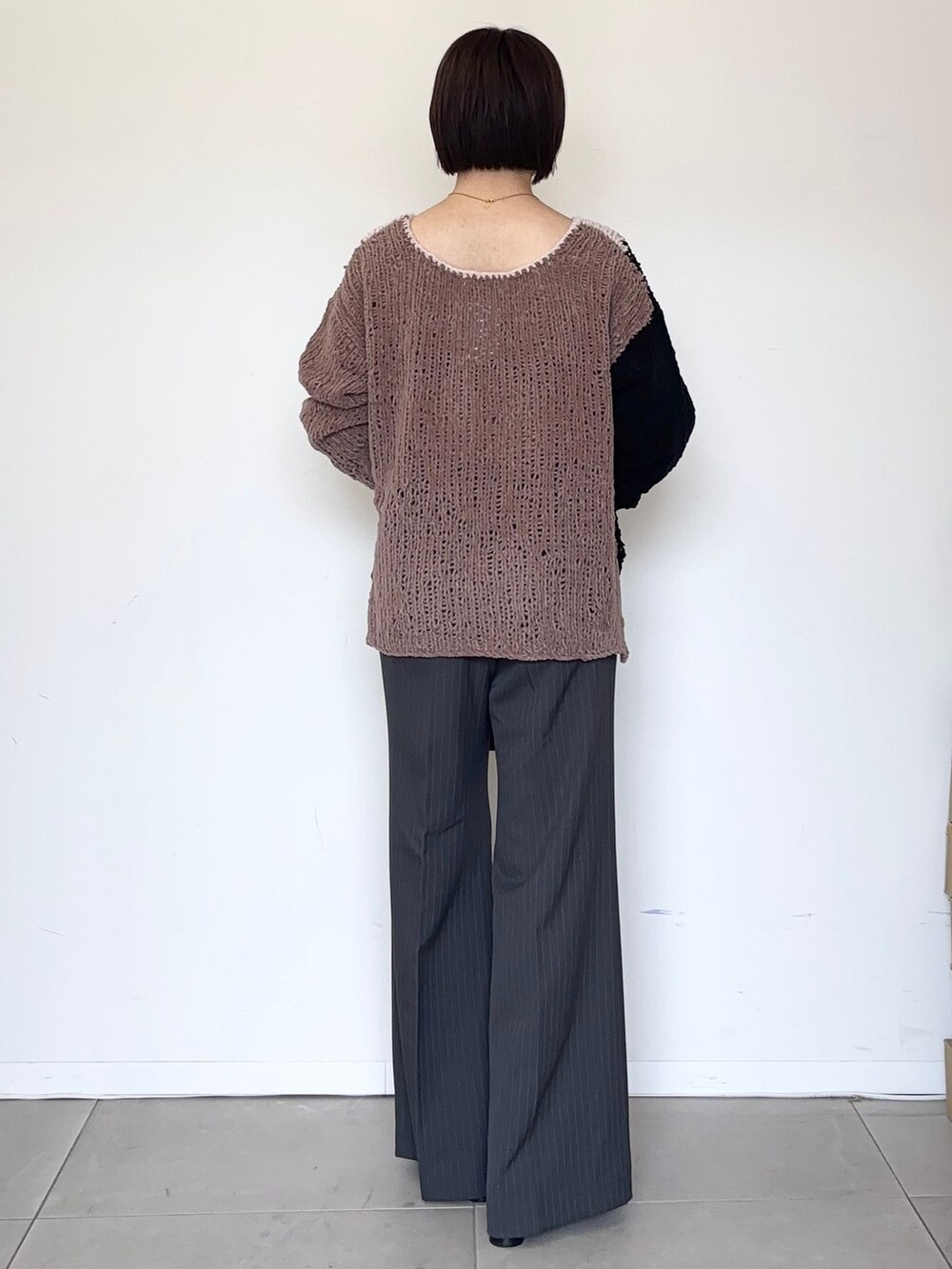 グレー系のスラックス、ブラウン系のニット/セーター、レッド系のボストンバッグを着用したレディースの秋コーディネートの3枚目の写真