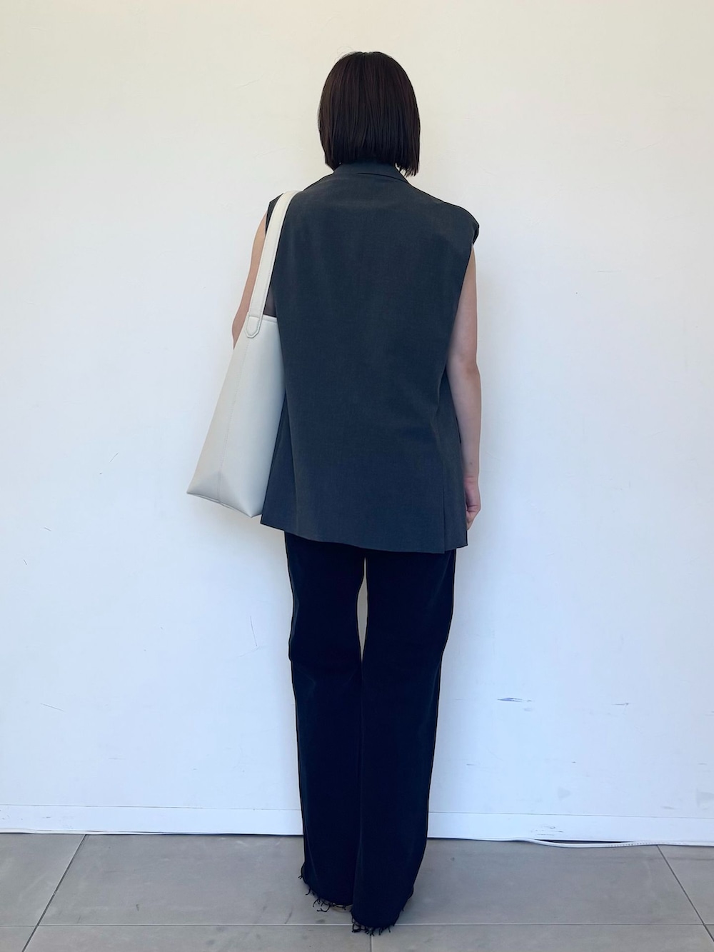 グレー系のベスト、ブラック系のデニムパンツ、ブラック系のキャミソールを着用したレディースの夏コーディネートの3枚目の写真