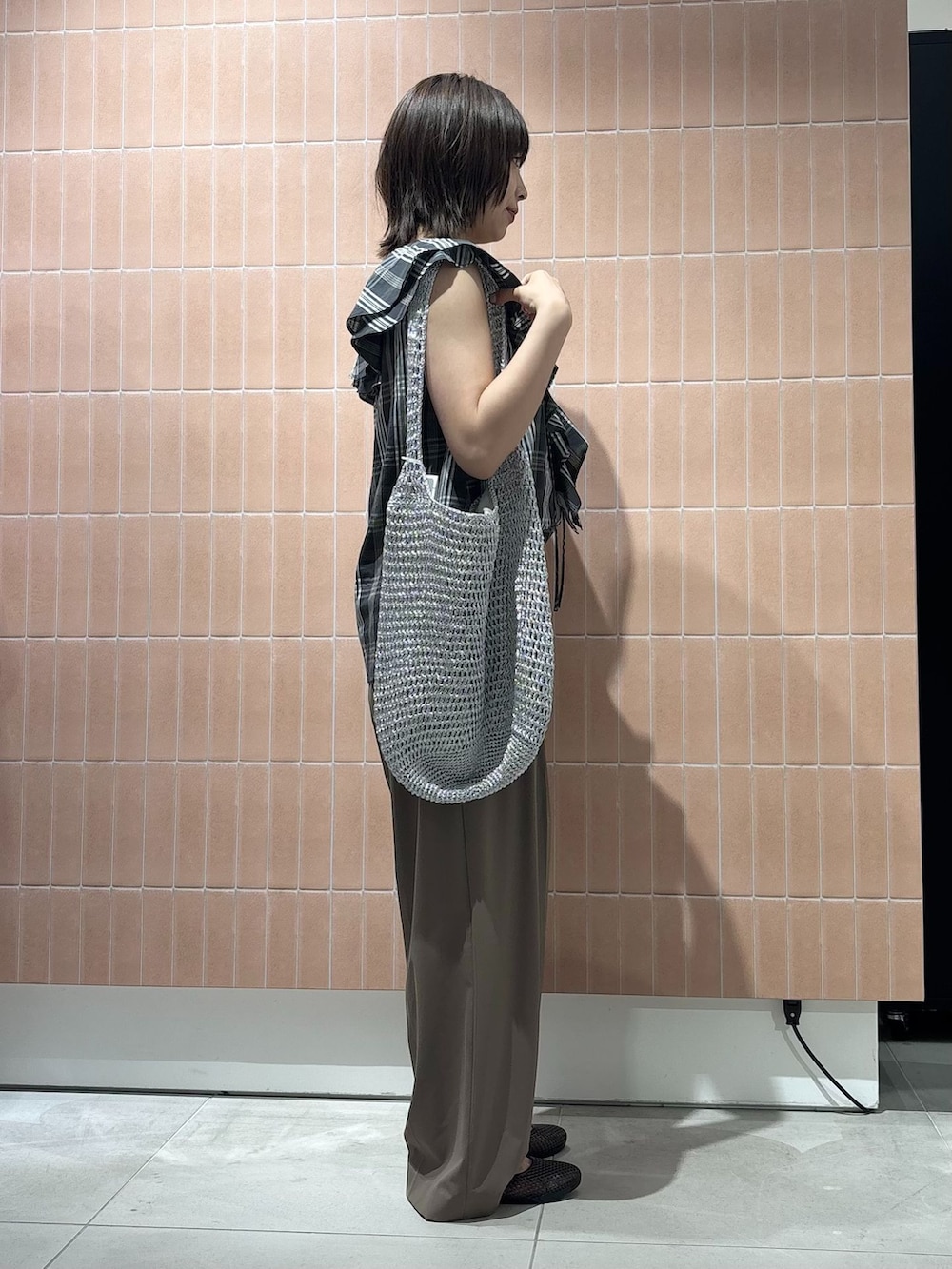 ベージュ系のスラックス、シルバー系のショルダーバッグ、ブラック系のパンプスを着用したレディースの夏コーディネートの4枚目の写真