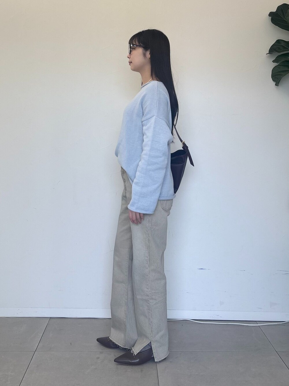 ベージュ系のデニムパンツ、ブルー系のニット/セーター、レッド系のショルダーバッグを着用したレディースの冬コーディネートの4枚目の写真