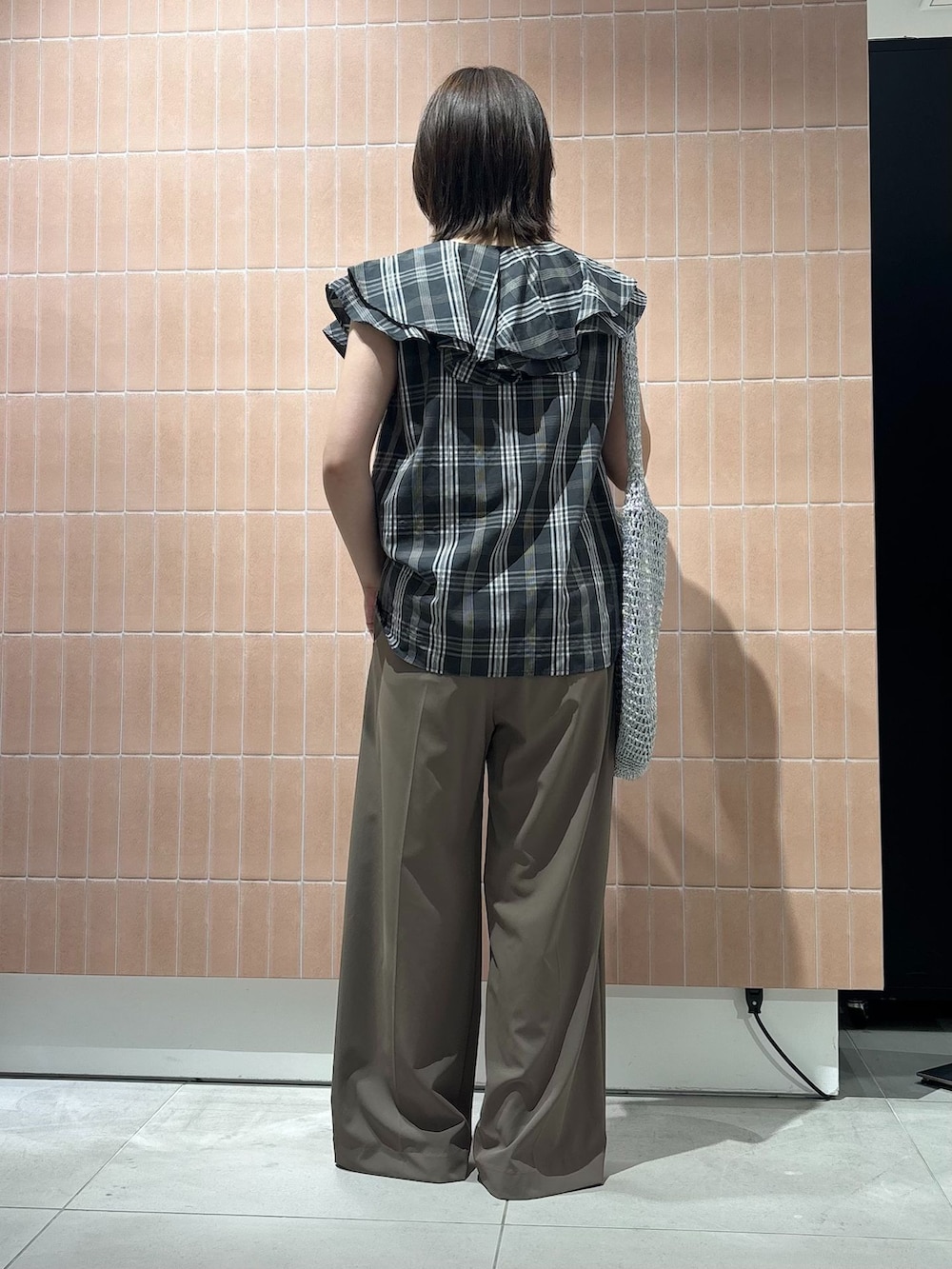 ベージュ系のスラックス、シルバー系のショルダーバッグ、ブラック系のパンプスを着用したレディースの夏コーディネートの3枚目の写真