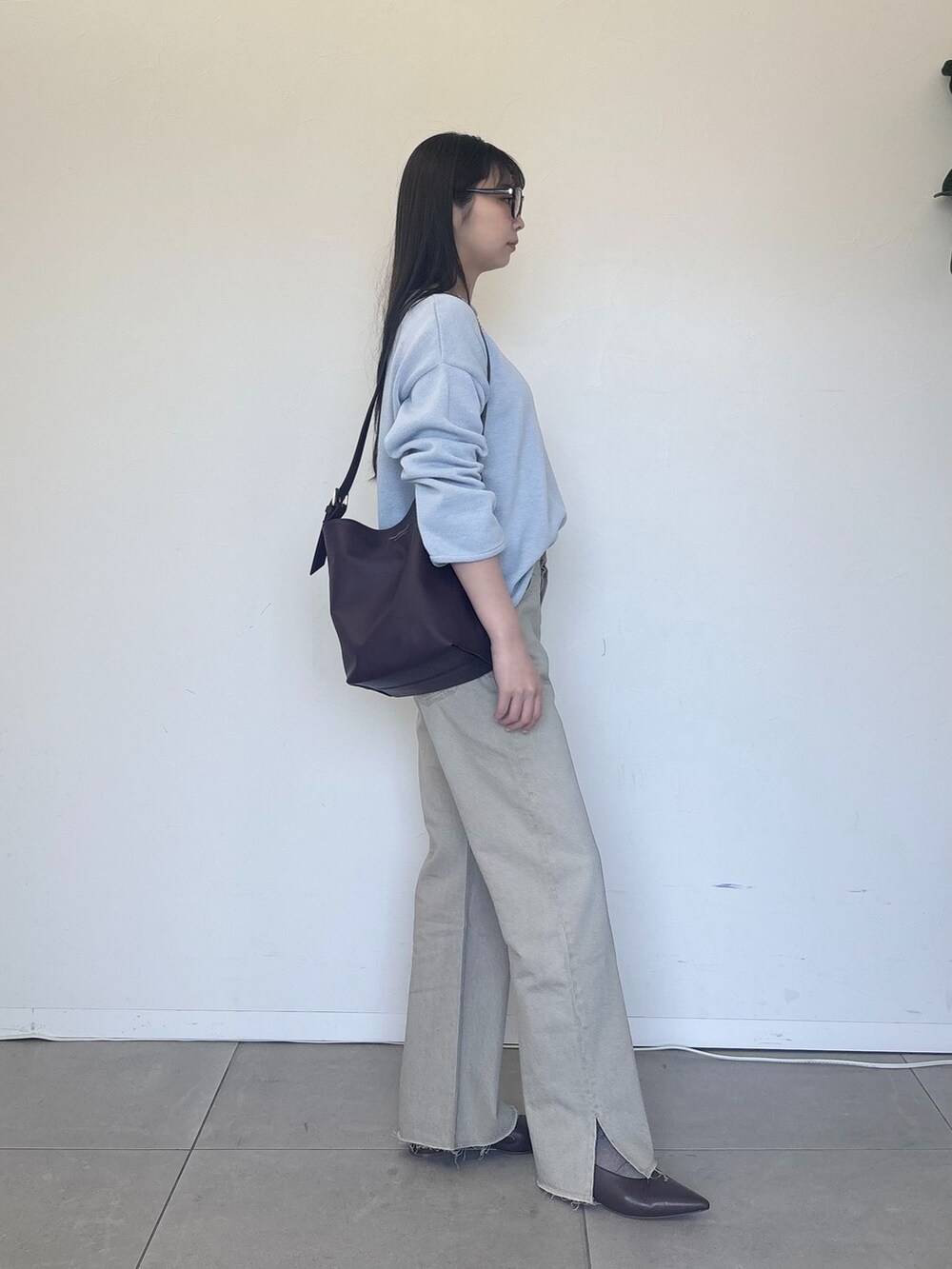 ベージュ系のデニムパンツ、ブルー系のニット/セーター、レッド系のショルダーバッグを着用したレディースの冬コーディネートの2枚目の写真