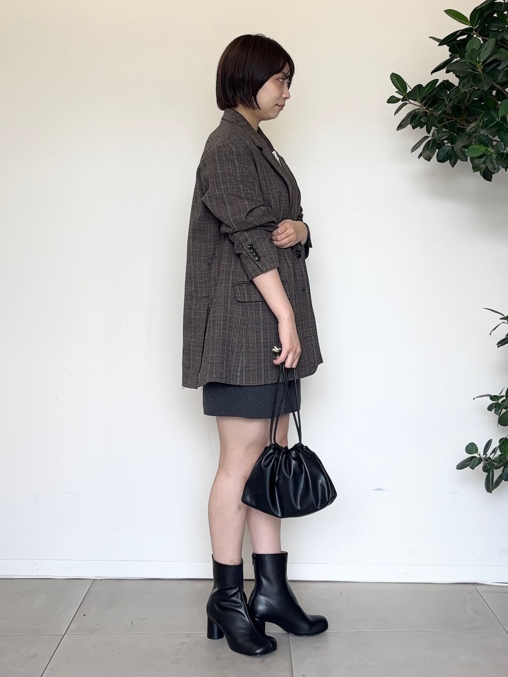 グレー系のスカート、グレー系のTシャツ/カットソー、ブラック系のクラッチバッグを着用したレディースの秋コーディネートの4枚目の写真