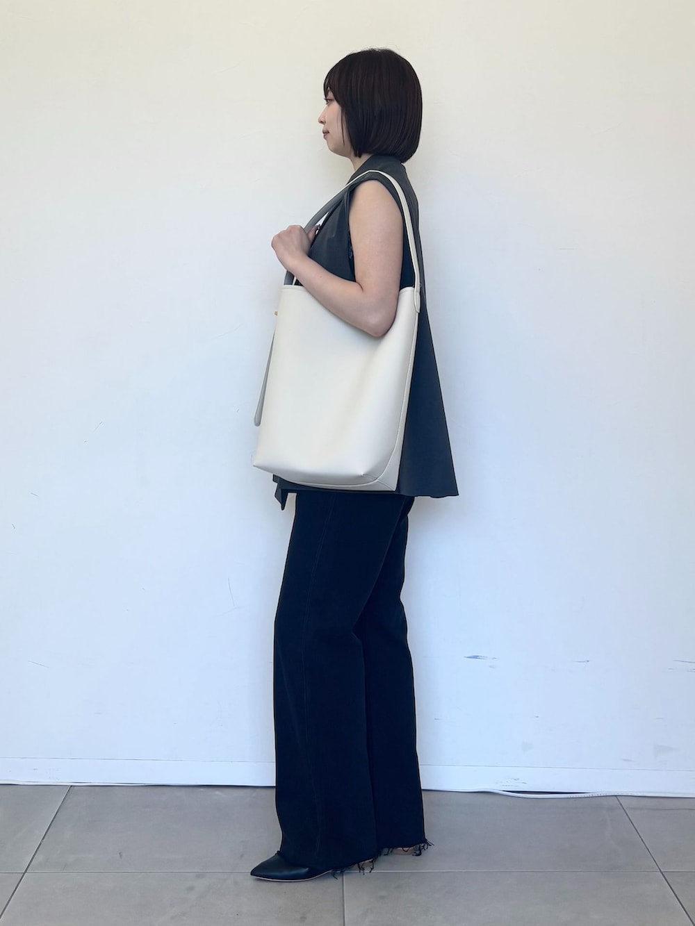 グレー系のベスト、ブラック系のデニムパンツ、ブラック系のキャミソールを着用したレディースの夏コーディネートの2枚目の写真