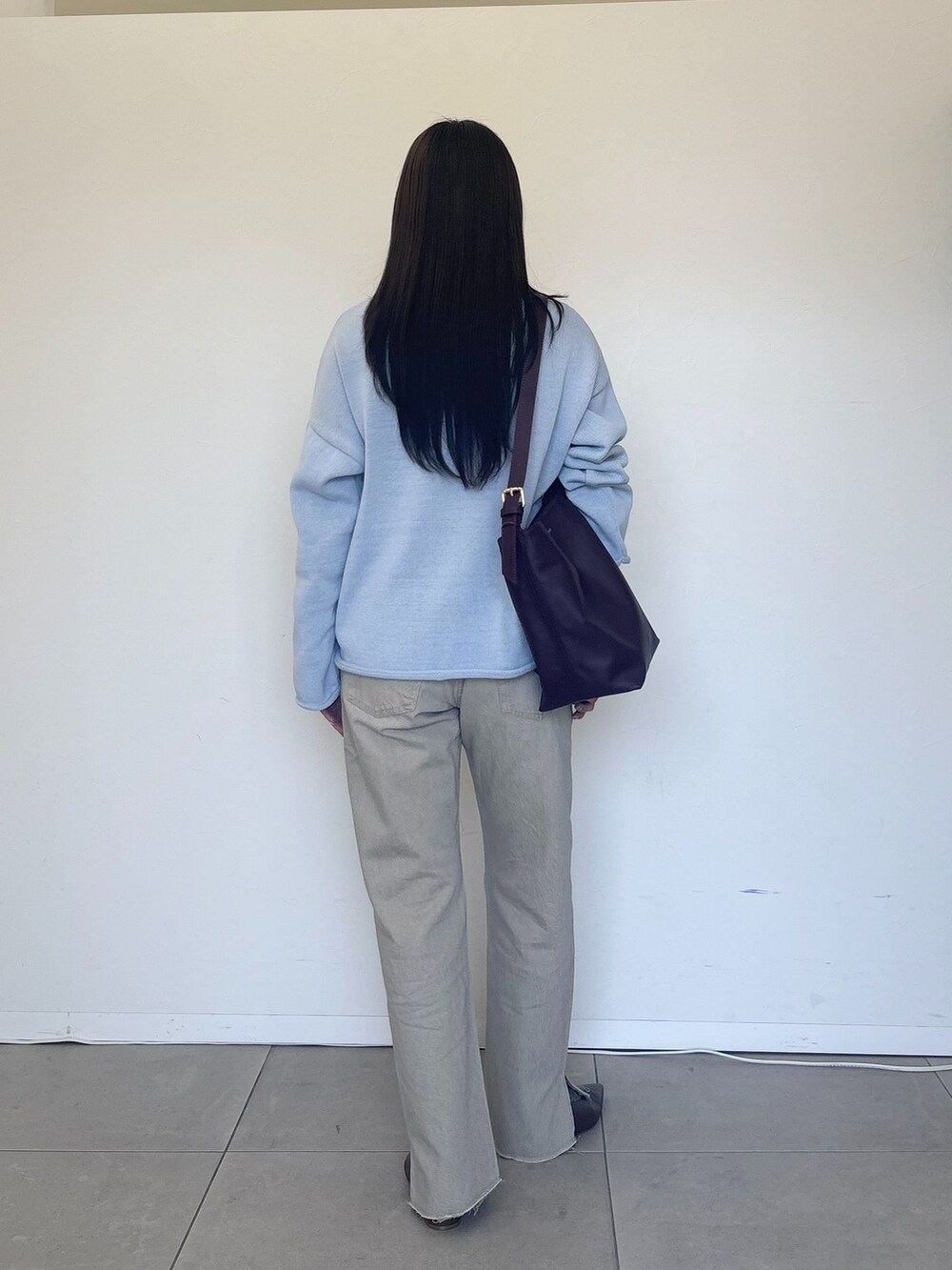 ベージュ系のデニムパンツ、ブルー系のニット/セーター、レッド系のショルダーバッグを着用したレディースの冬コーディネートの3枚目の写真