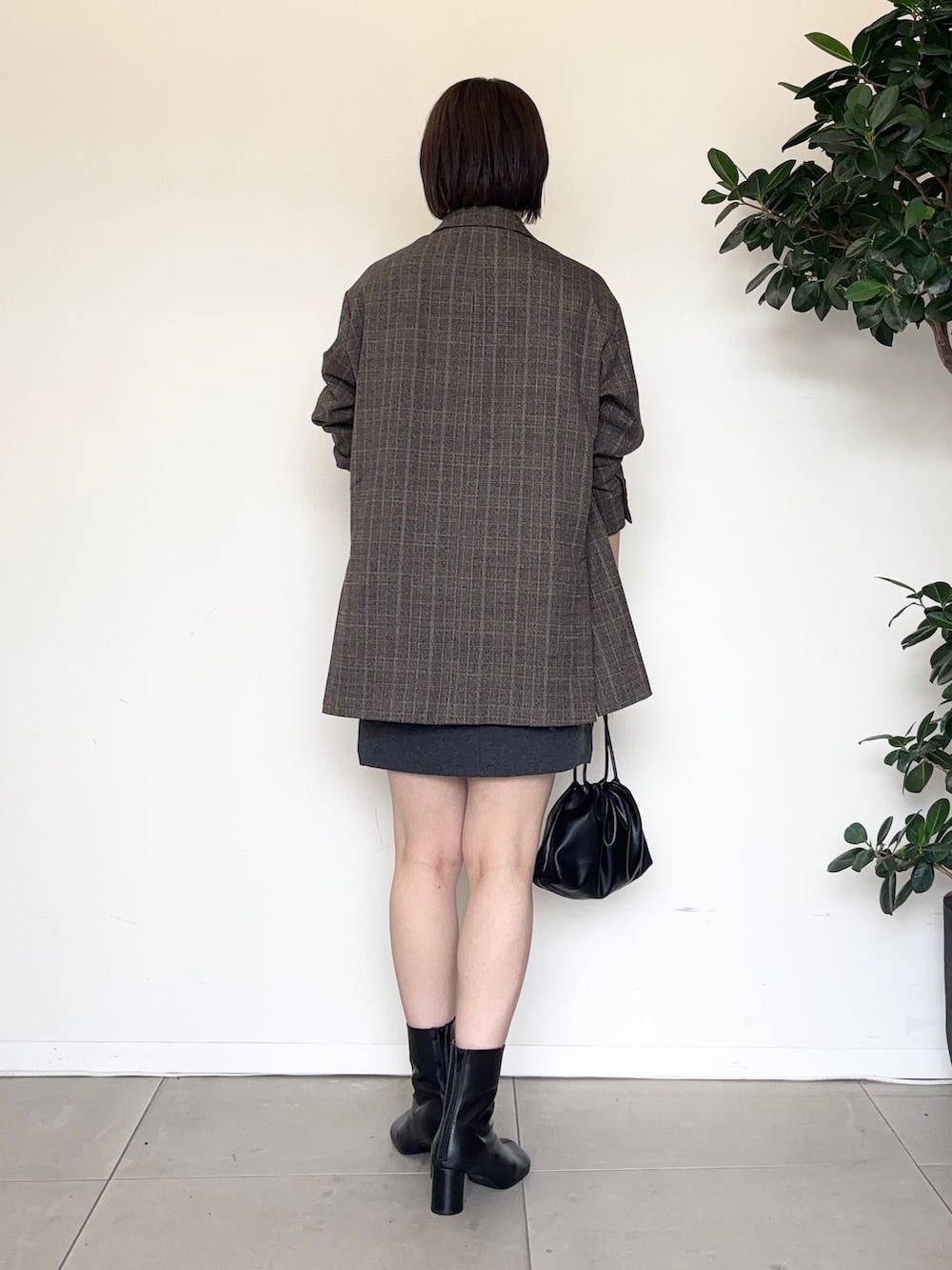 グレー系のスカート、グレー系のTシャツ/カットソー、ブラック系のクラッチバッグを着用したレディースの秋コーディネートの3枚目の写真