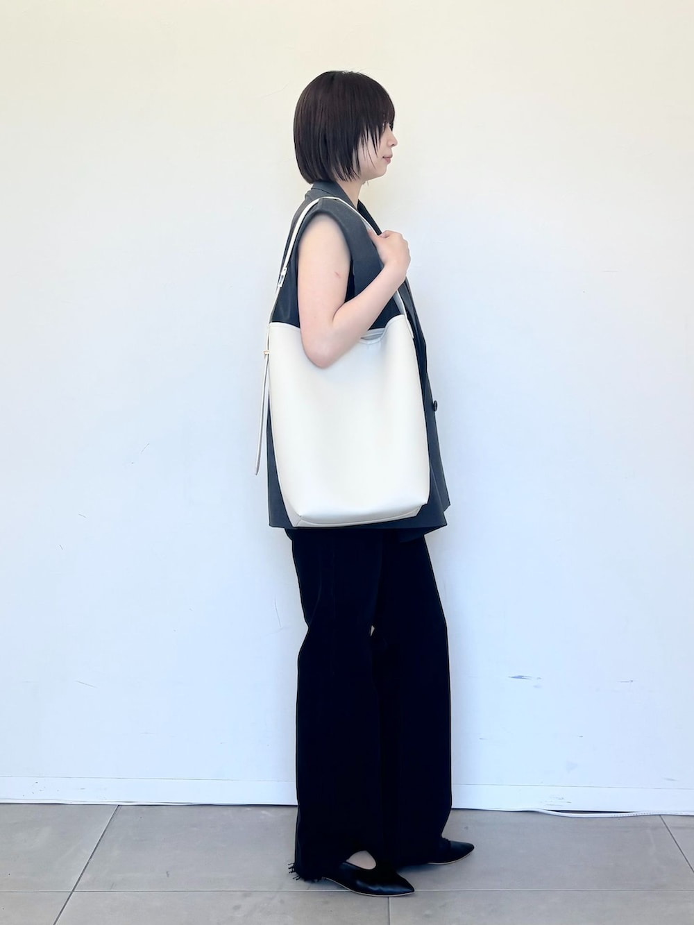 グレー系のベスト、ブラック系のデニムパンツ、ブラック系のキャミソールを着用したレディースの夏コーディネートの4枚目の写真
