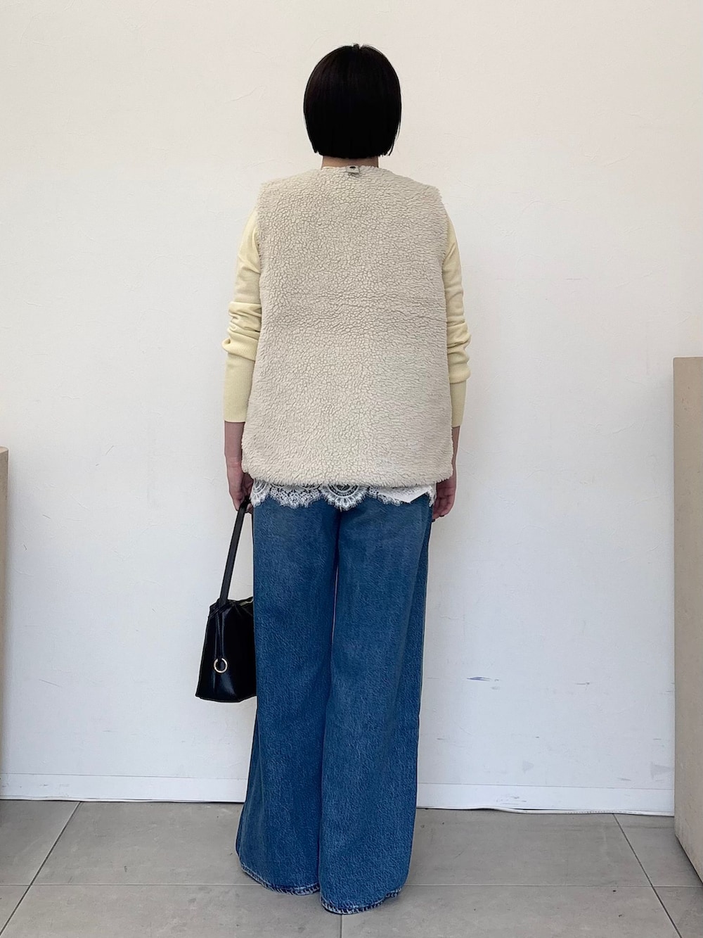 ホワイト系のその他アウター、ブルー系のデニムパンツ、イエロー系のニット/セーターを着用したレディースの秋コーディネートの4枚目の写真