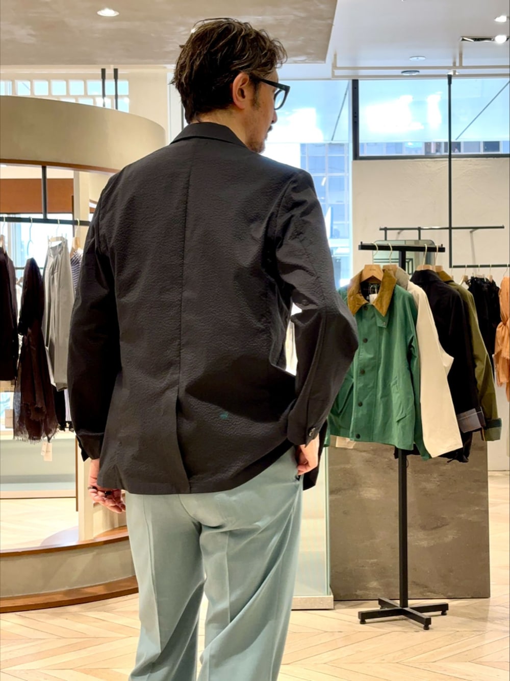 ブラック系のテーラードジャケット、グリーン系のスラックス、ブラウン系のTシャツ/カットソーを着用したメンズの春コーディネートの4枚目の写真