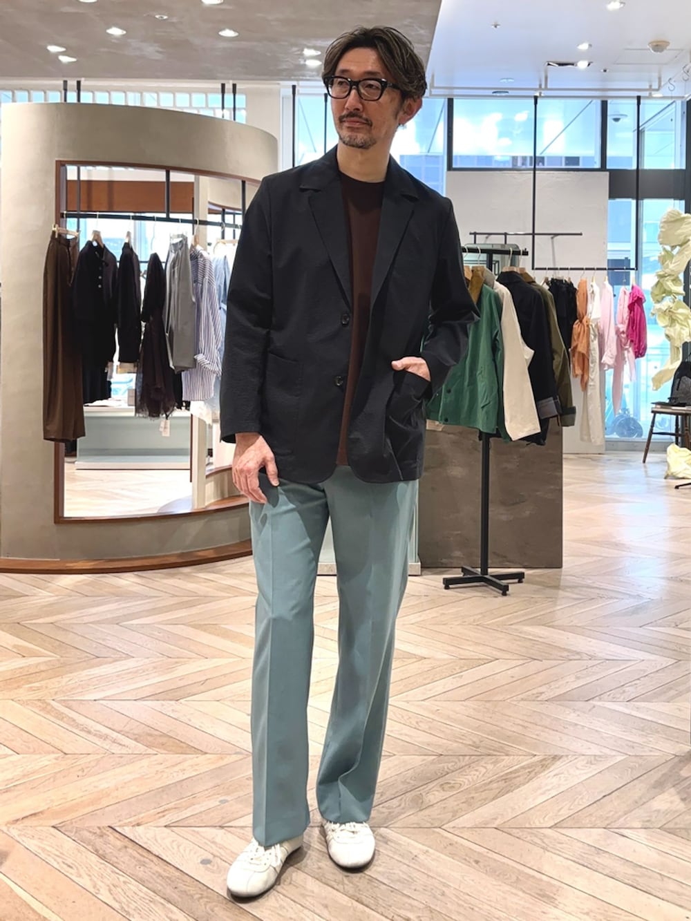 ブラック系のテーラードジャケット、グリーン系のスラックス、ブラウン系のTシャツ/カットソーを着用したメンズの春コーディネートの2枚目の写真