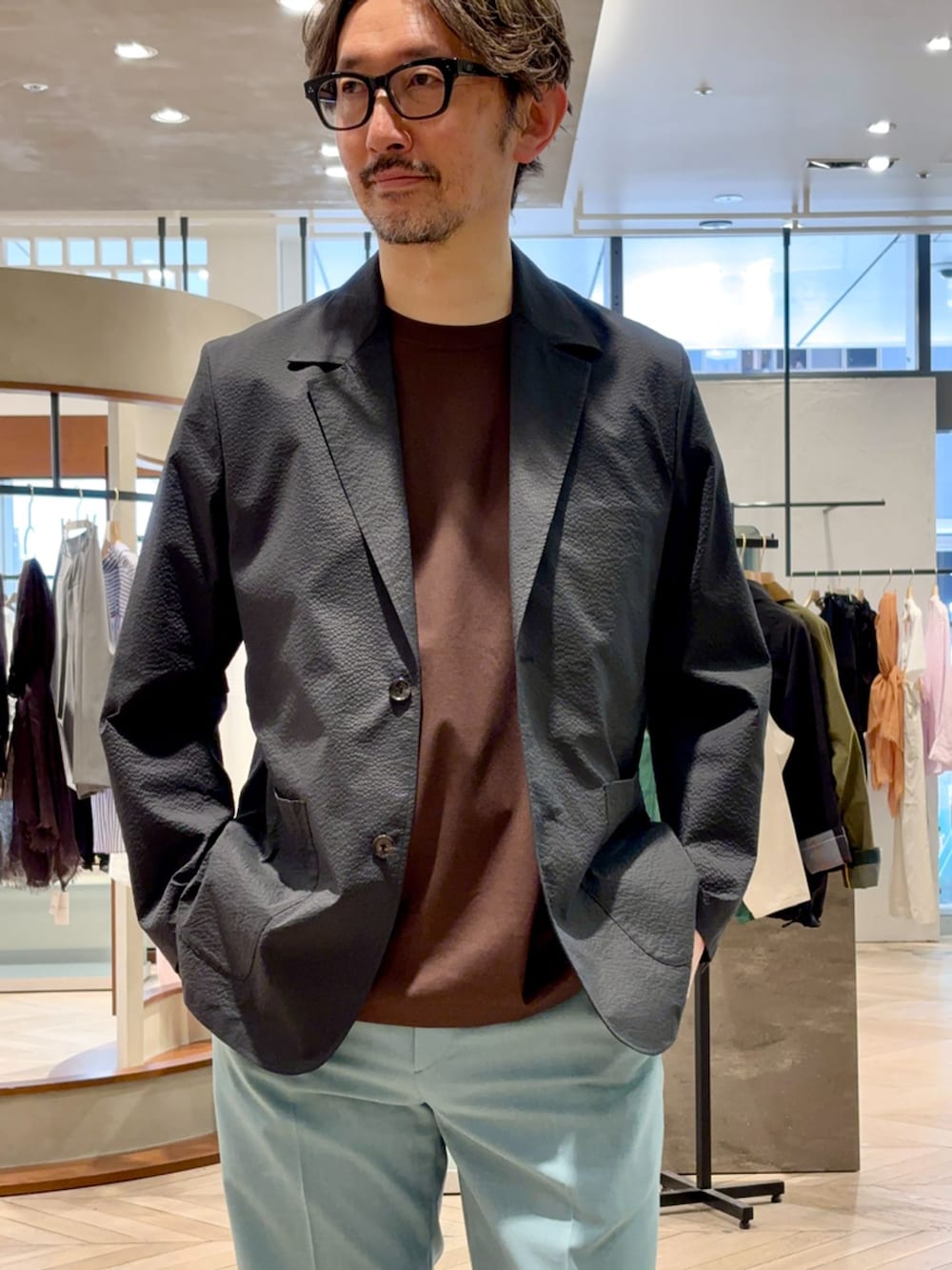 ブラック系のテーラードジャケット、グリーン系のスラックス、ブラウン系のTシャツ/カットソーを着用したメンズの春コーディネートの3枚目の写真