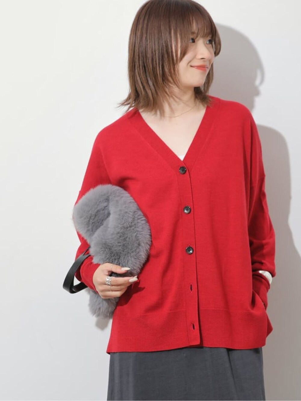 グレー系のスカート、レッド系のカーディガン/ボレロ、グレー系のハンドバッグを着用したレディースの夏コーディネートの6枚目の写真