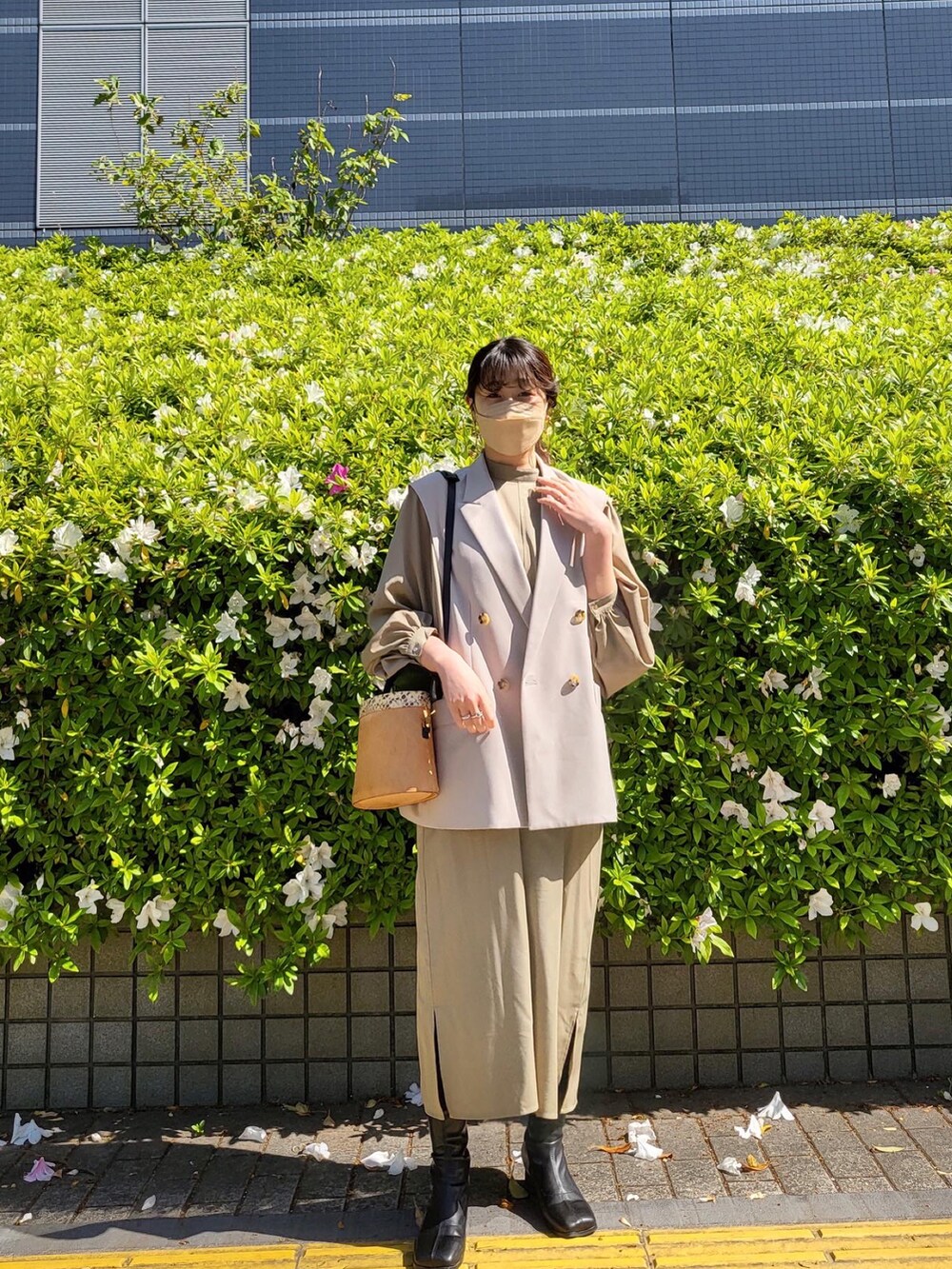ホワイト系のベスト、ベージュ系のワンピース、ブラック系のブーツを着用したレディースの春コーディネートの2枚目の写真