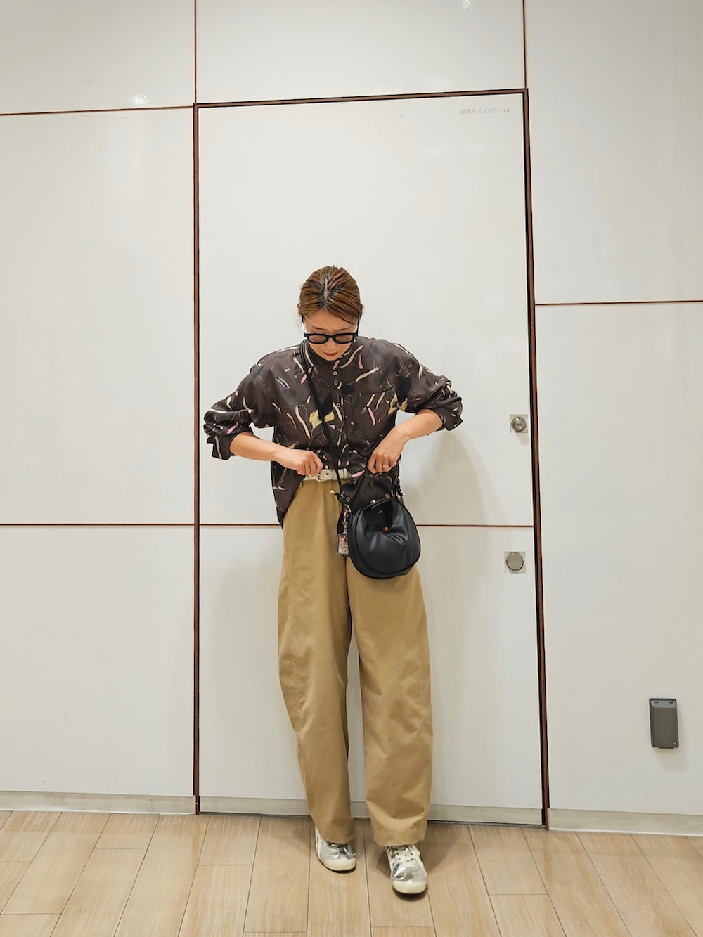 ブラウン系のシャツ/ブラウス、ベージュ系のパンツ、シルバー系のスニーカーを着用したレディースの秋コーディネートの2枚目の写真