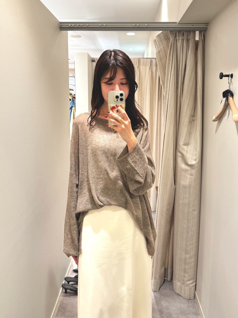 ホワイト系のスカート、ブラウン系のニット/セーター、ブラウン系のボストンバッグを着用したレディースの秋コーディネートの2枚目の写真