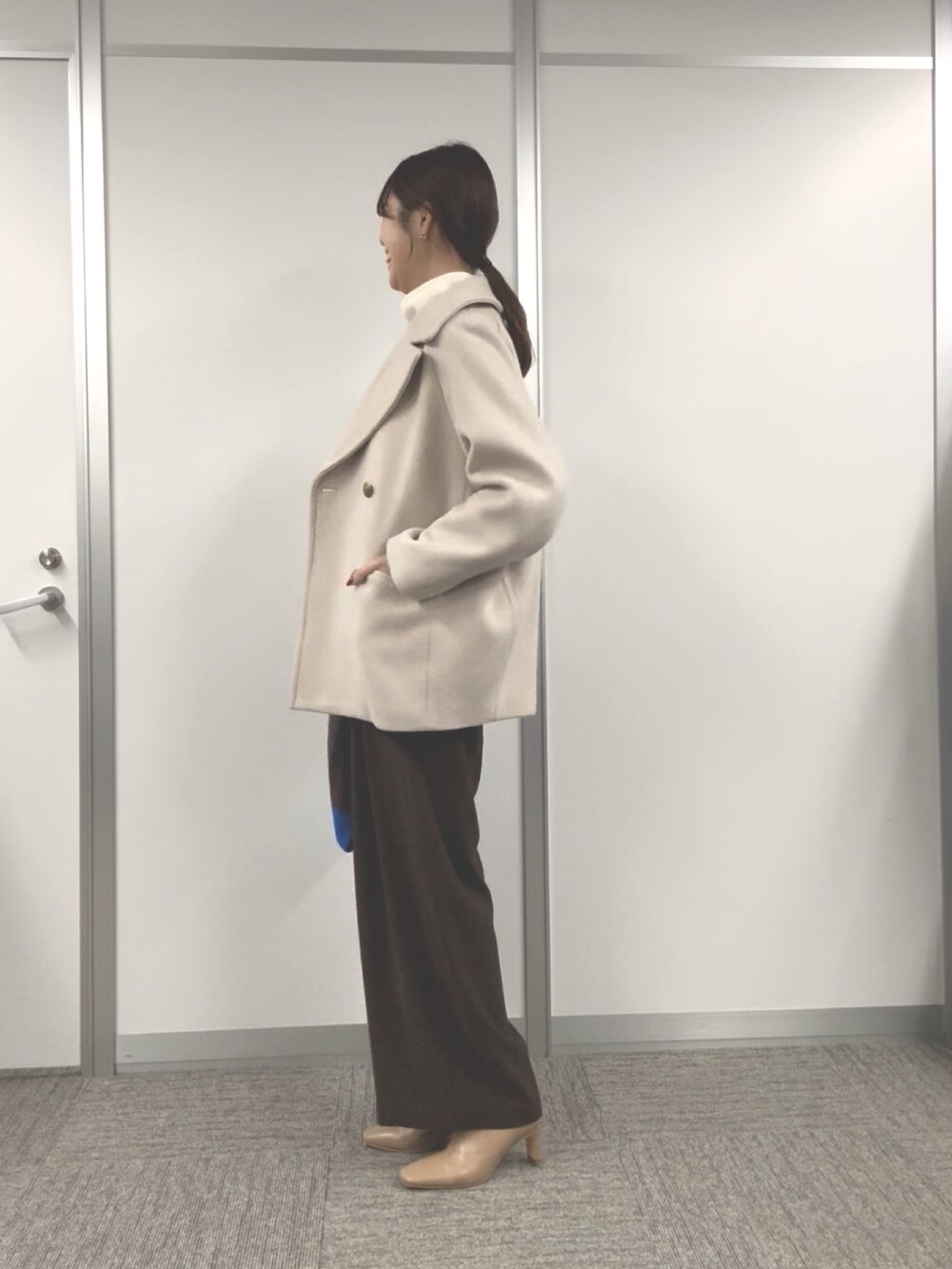 ベージュ系のピーコート、ブラウン系のスラックス、パープル系のストール/ショールを着用したレディースの秋コーディネートの2枚目の写真