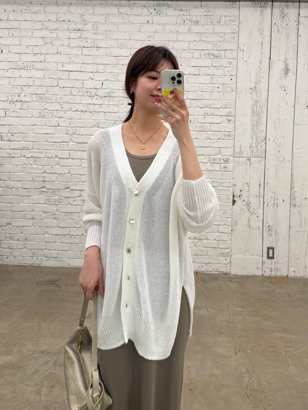 ブラウン系のワンピース、ゴールド系のショルダーバッグ、ホワイト系のカーディガン/ボレロを着用したレディースの春コーディネートの2枚目の写真