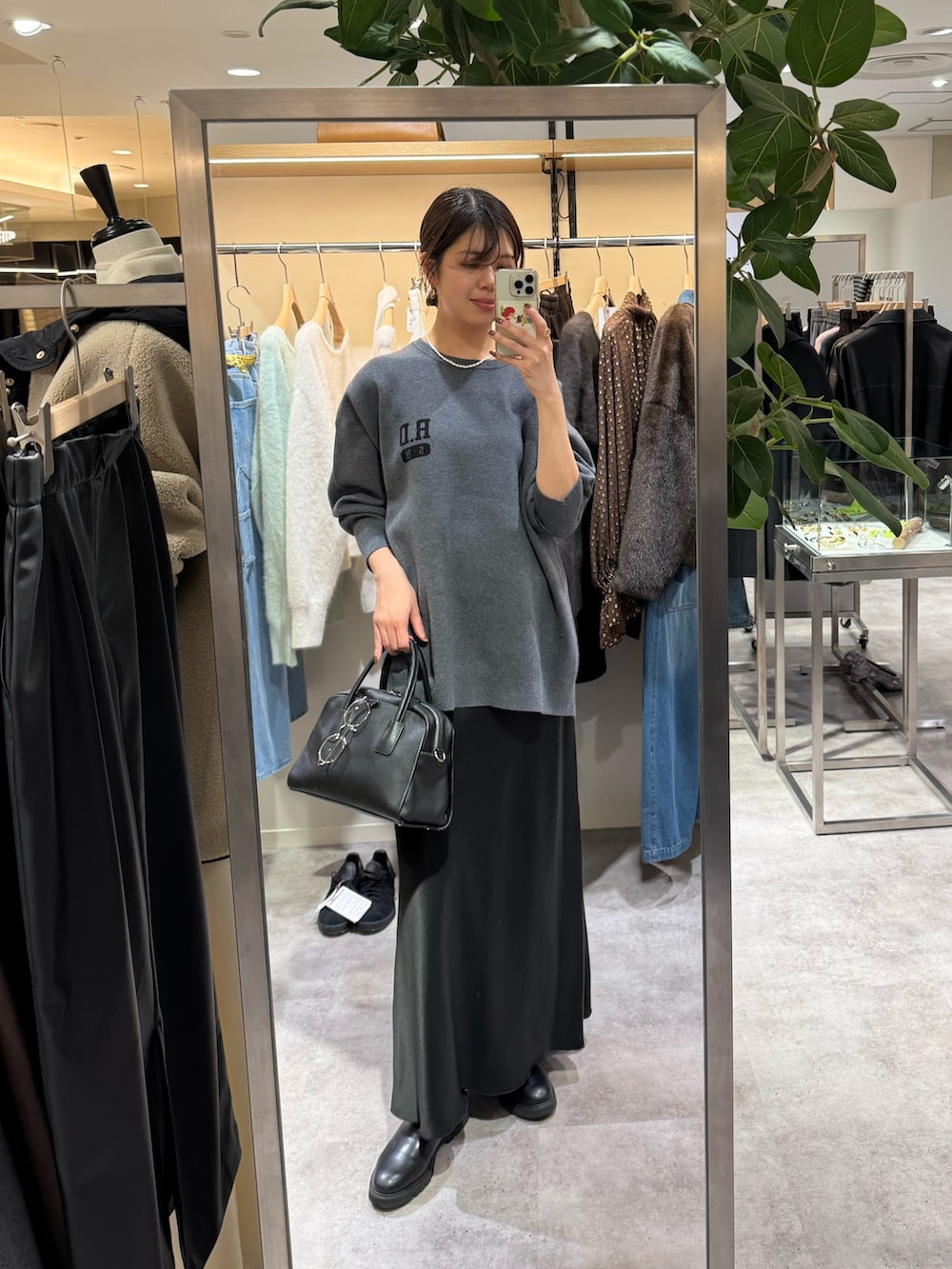 ブラック系のその他アウター、ブラック系のスカート、イエロー系のハンドバッグを着用したレディースの秋コーディネートの2枚目の写真