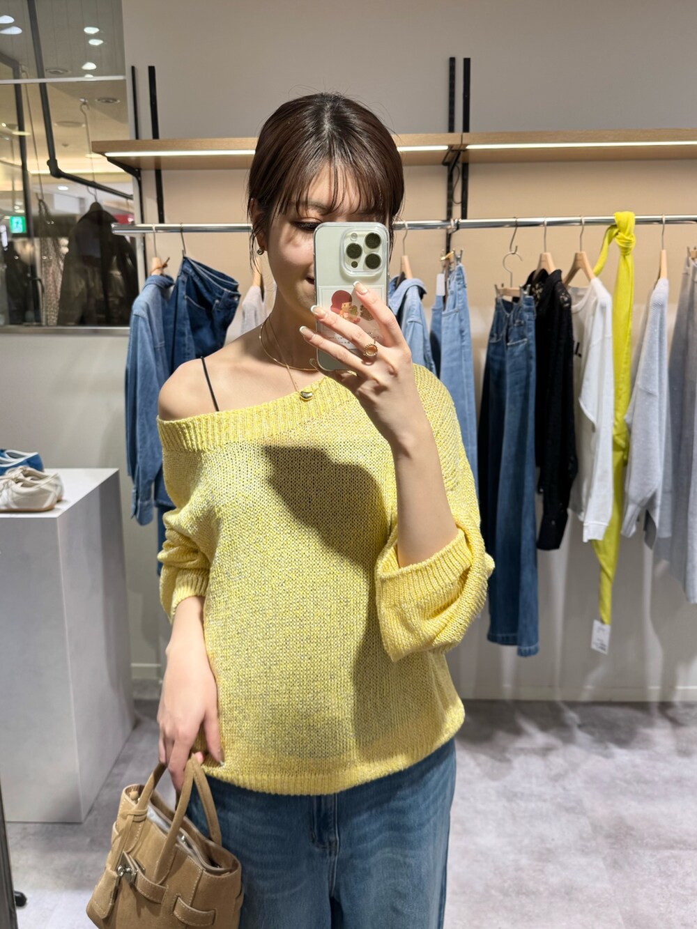 イエロー系のニット/セーター、ブルー系のデニムパンツ、ベージュ系のトートバッグを着用したレディースの冬コーディネートの2枚目の写真