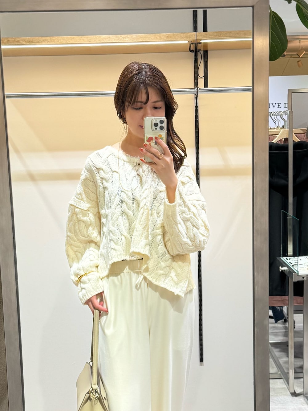 ホワイト系のニット/セーター、ホワイト系のその他パンツ、ベージュ系のハンドバッグを着用したレディースの冬コーディネートの2枚目の写真