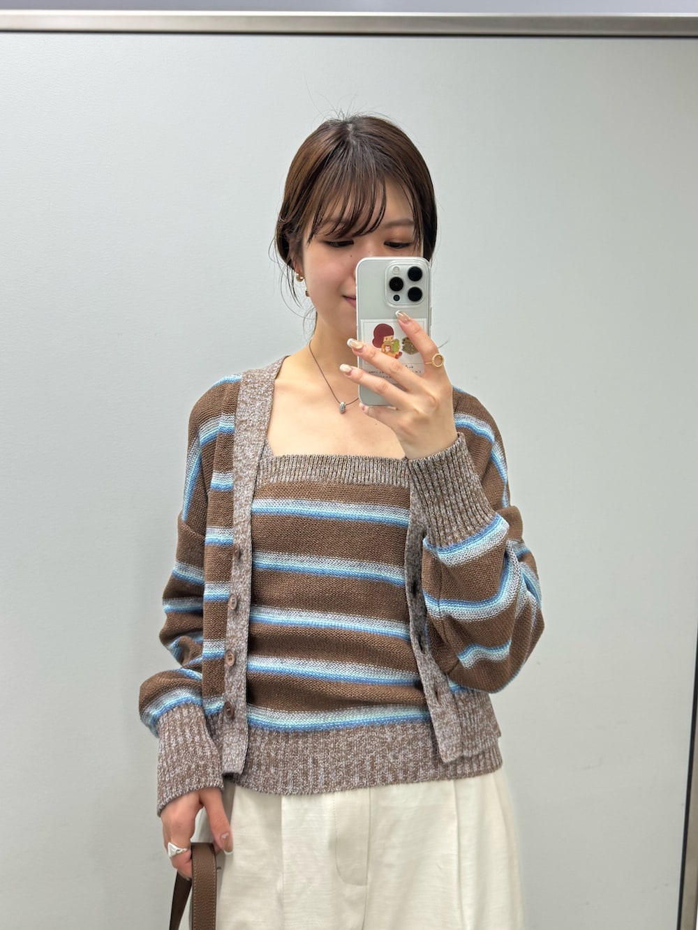 ホワイト系のチノパンツ、ブラウン系のカーディガン/ボレロ、ブラウン系のキャミソールを着用したレディースの冬コーディネートの2枚目の写真