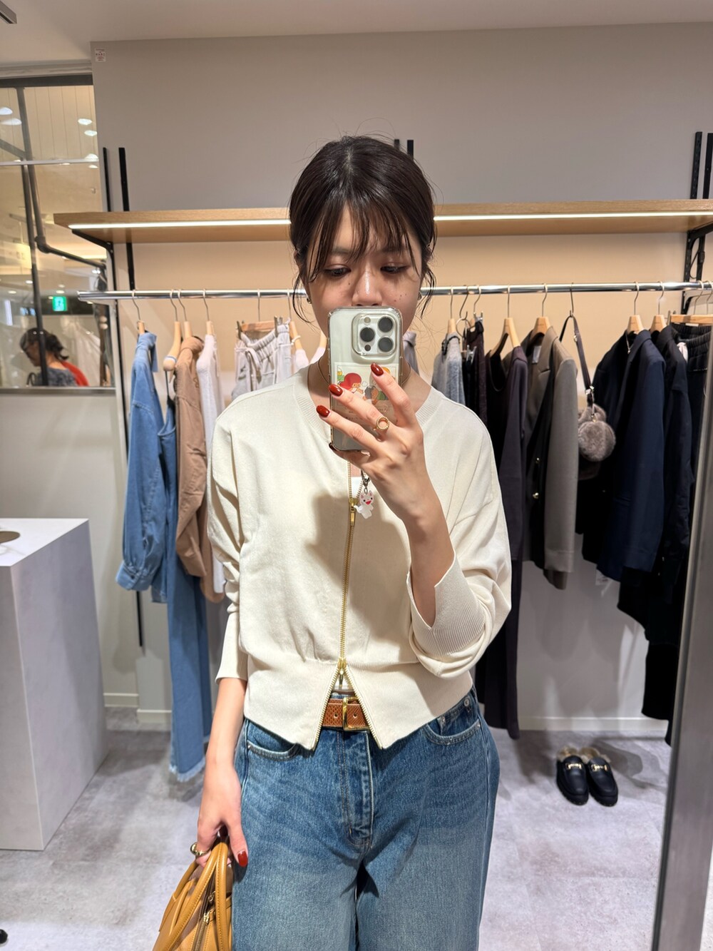 ブルー系のデニムパンツ、ホワイト系のカーディガン/ボレロ、ブラウン系のパンプスを着用したレディースの秋コーディネートの2枚目の写真