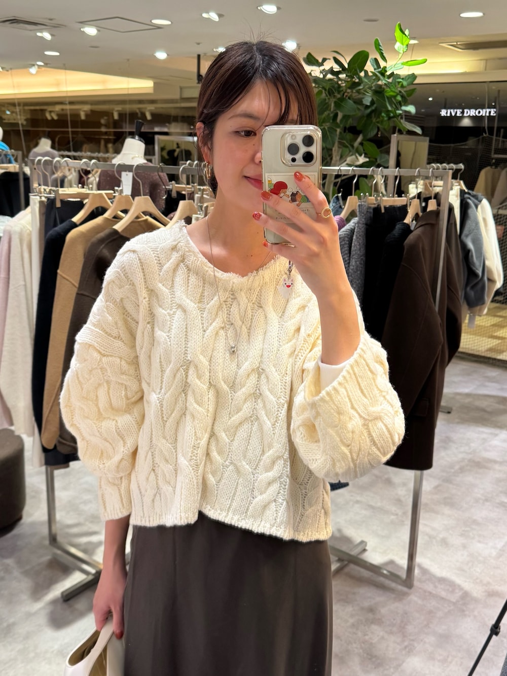 ホワイト系のニット/セーター、ブラウン系のスカート、ホワイト系のハンドバッグを着用したレディースの秋コーディネートの2枚目の写真