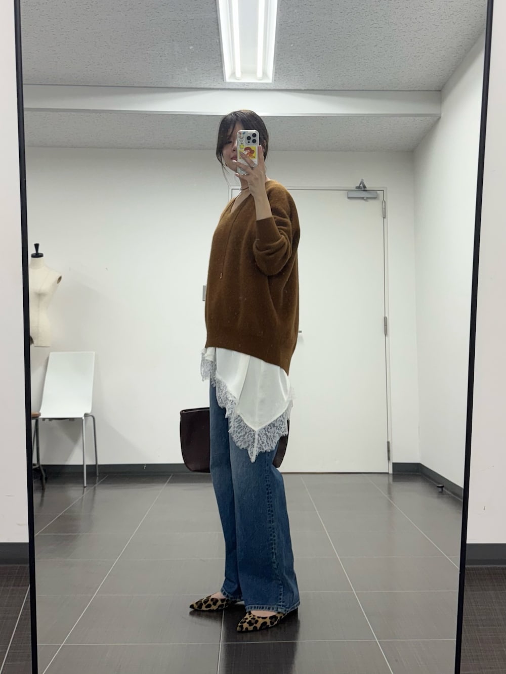 イエロー系のニット/セーター、ホワイト系のキャミソール、ブルー系のデニムパンツを着用したレディースの秋コーディネートの2枚目の写真