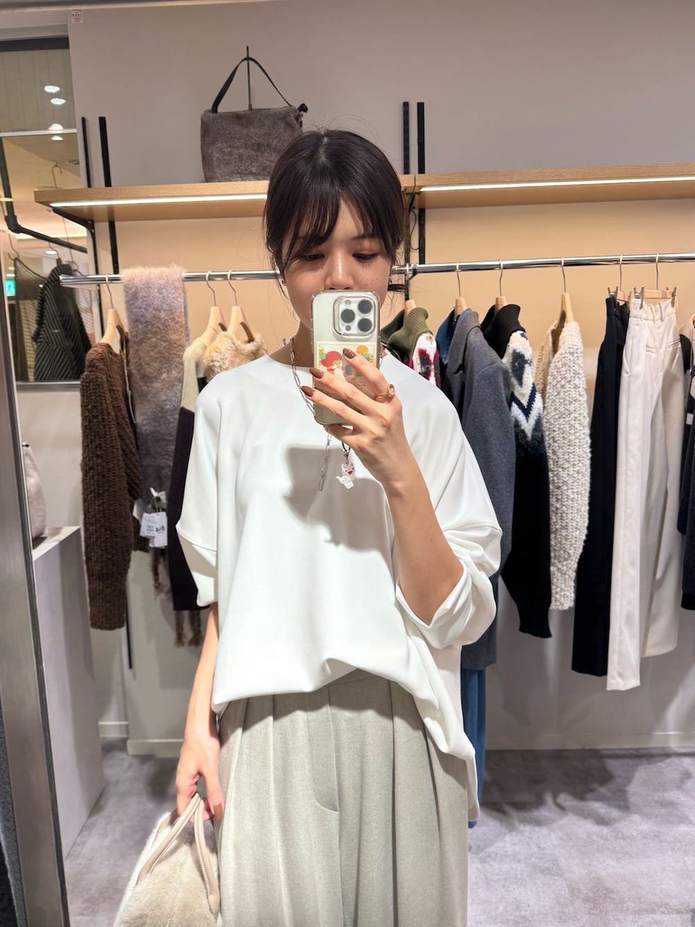 ベージュ系のスラックス、ホワイト系のTシャツ/カットソー、ベージュ系のボストンバッグを着用したレディースの秋コーディネートの2枚目の写真