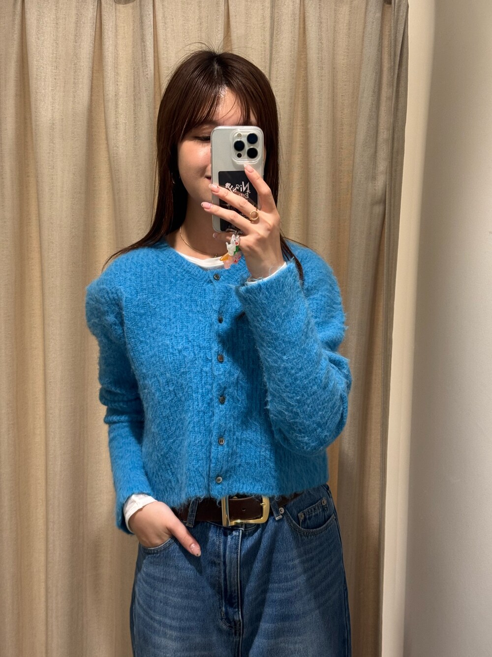 ブルー系のカーディガン/ボレロ、ブルー系のデニムパンツ、ブラック系のハンドバッグを着用したレディースの冬コーディネートの2枚目の写真