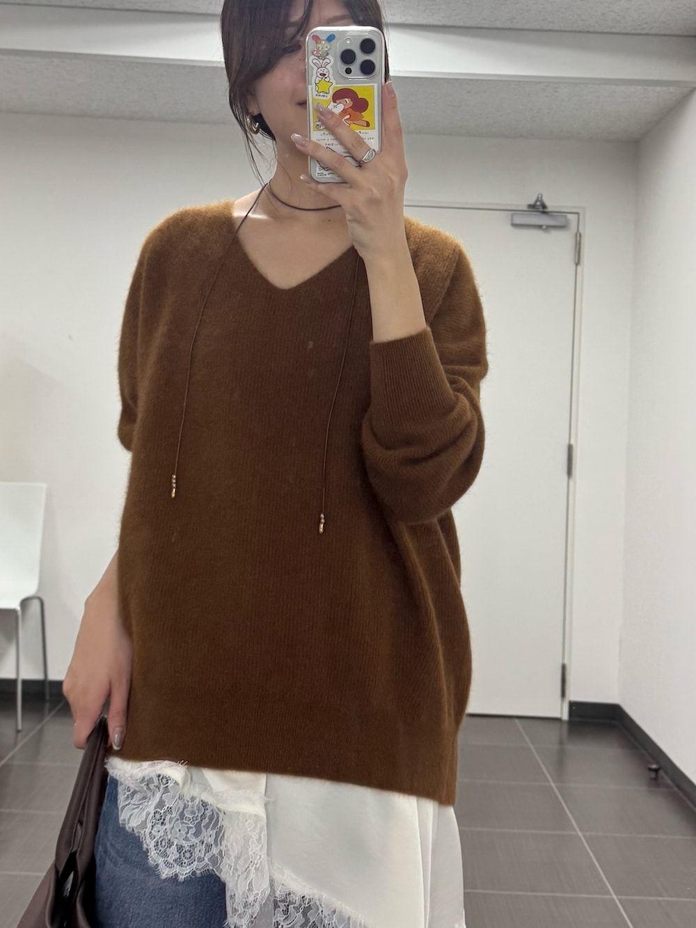 イエロー系のニット/セーター、ホワイト系のキャミソール、ブルー系のデニムパンツを着用したレディースの秋コーディネートの3枚目の写真