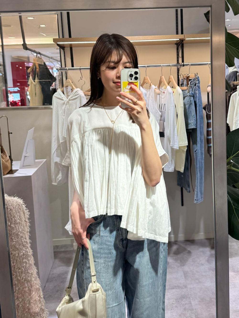 ブルー系のデニムパンツ、ホワイト系のシャツ/ブラウス、ゴールド系のショルダーバッグを着用したレディースの春コーディネートの2枚目の写真