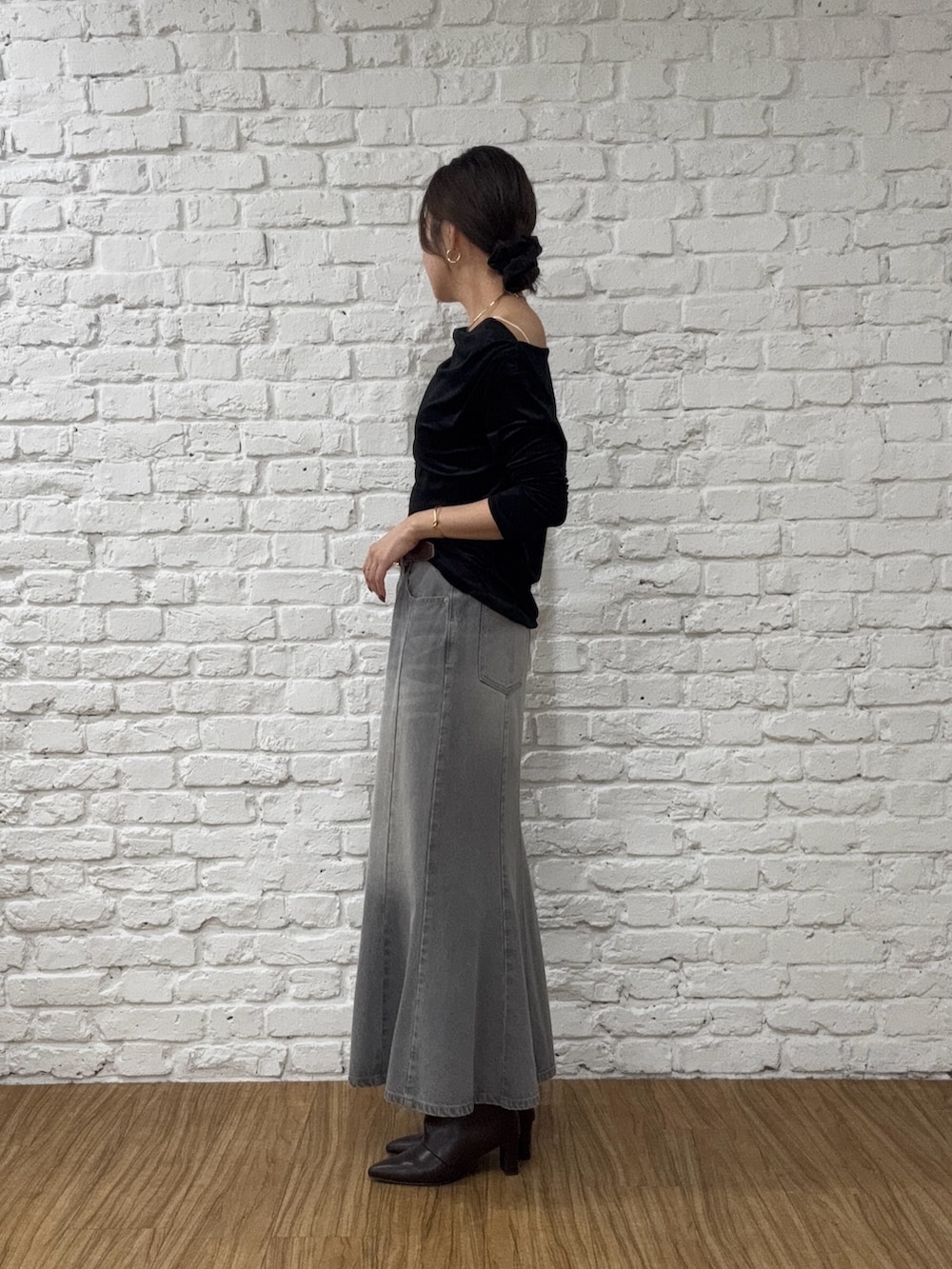 グレー系のデニムスカート、ブラック系のTシャツ/カットソー、ブラウン系のブーツを着用したレディースの秋コーディネートの2枚目の写真